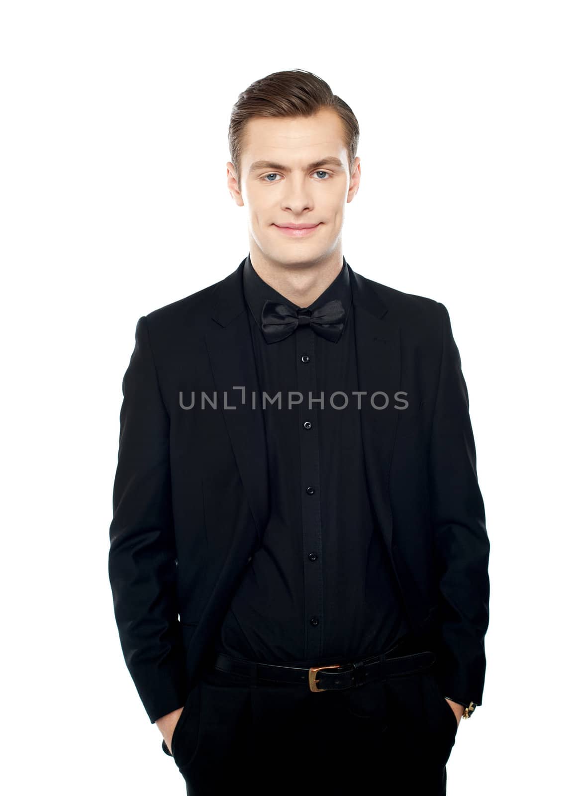 Elegant positive young guy posing with arms in pocket dressed in black suit
