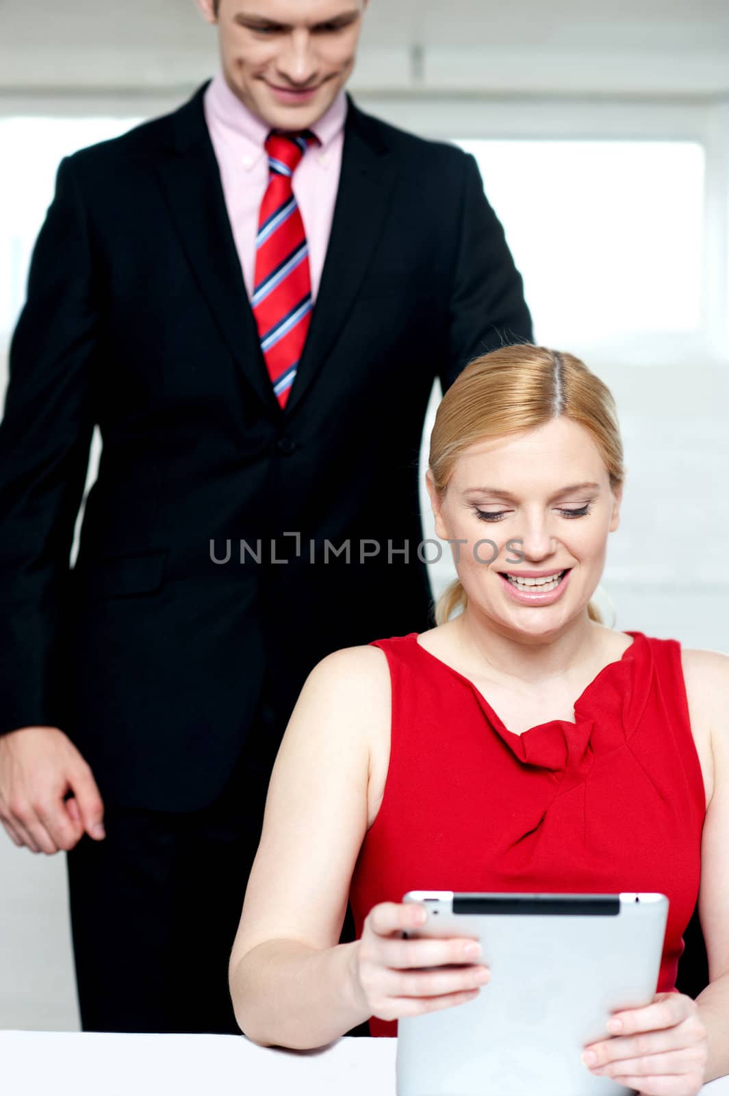 Boss operating tablet pc and assistant looking by stockyimages