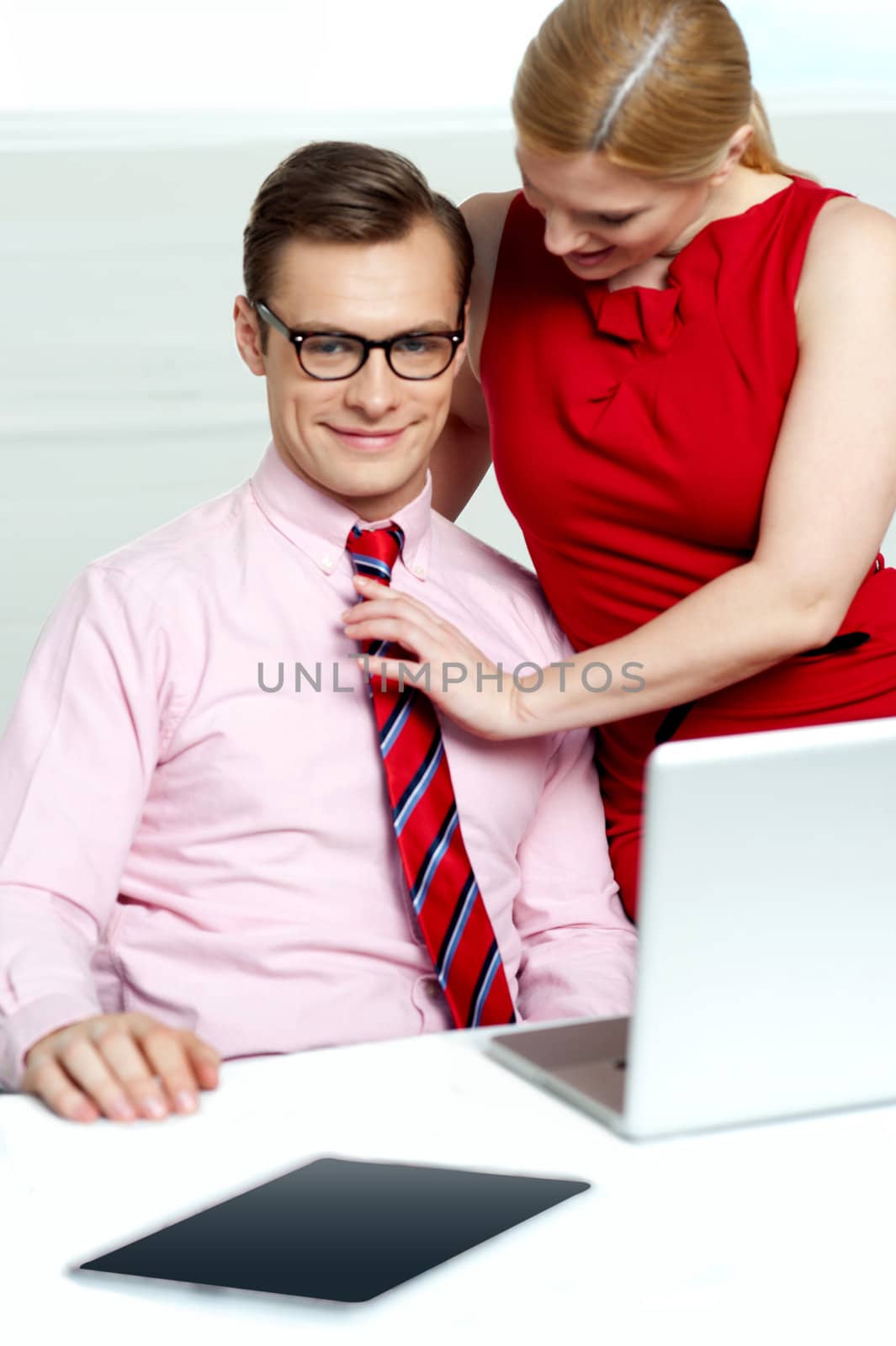 Female adjusting her co-workers tie by stockyimages