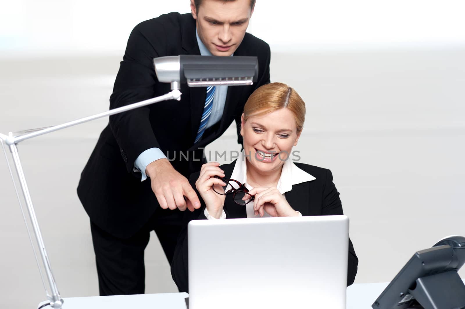 Man pointing finger at laptop screen to explain problem to female colleague