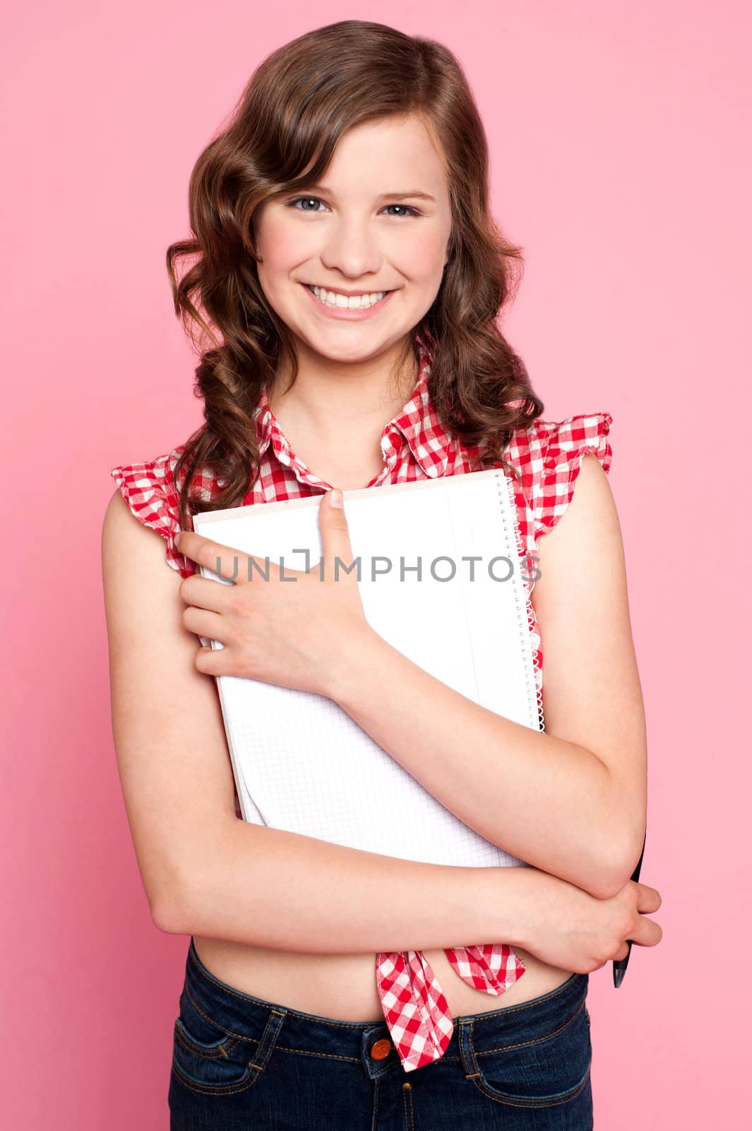 Joyful teenage girl holding spiral notebook. Educational concept