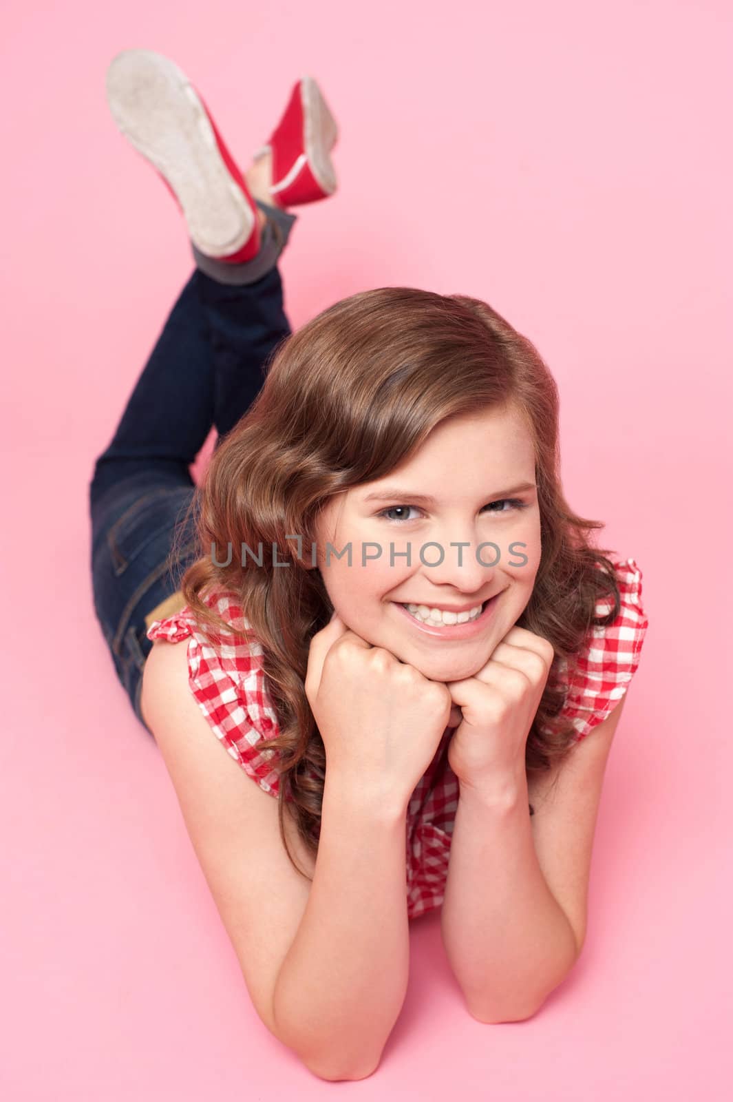 Beautiful girl posing with hands on chin. Lying on studio floor
