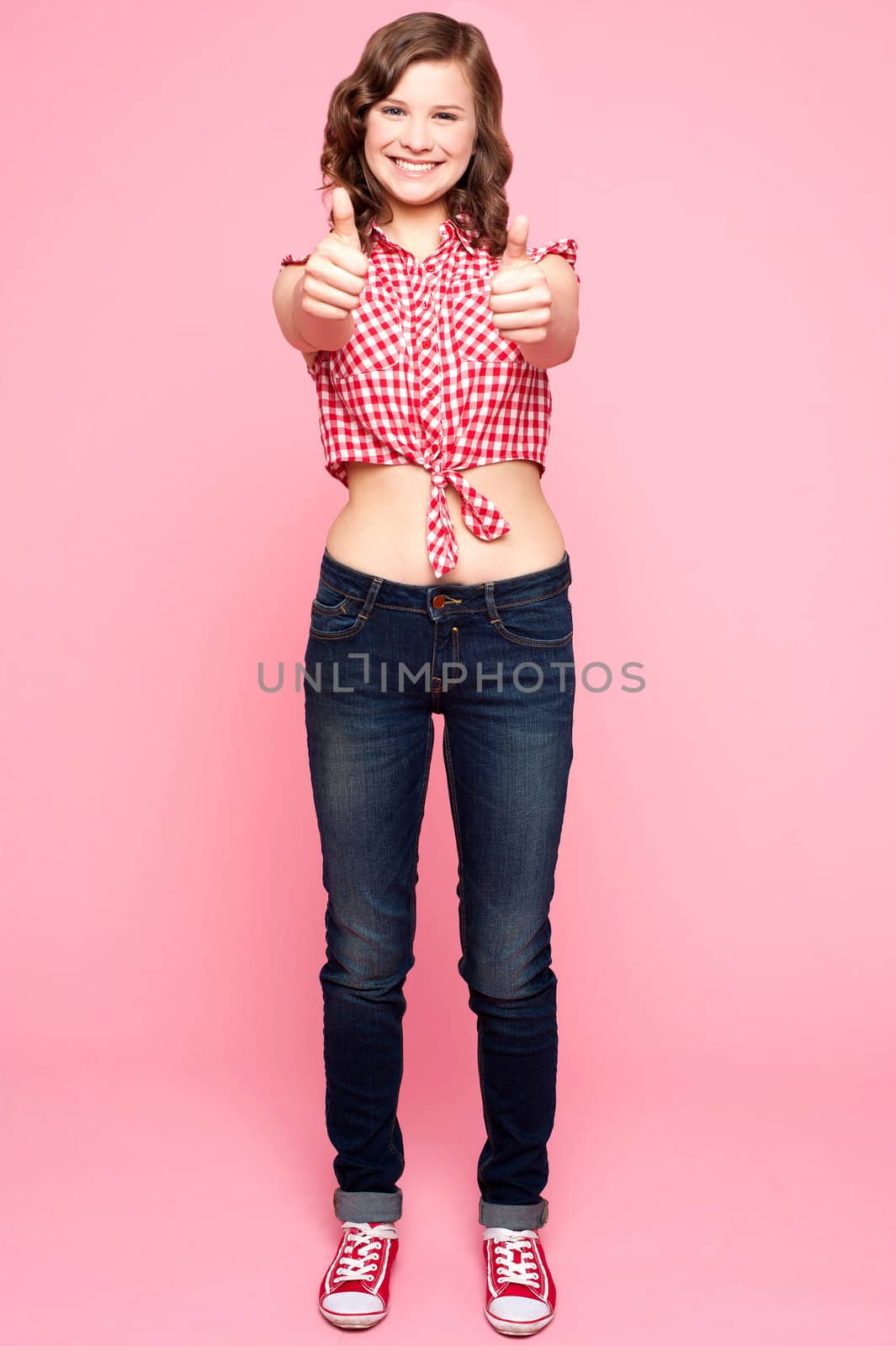 Glamorous girl gesturing double thumbs up, full length portrait