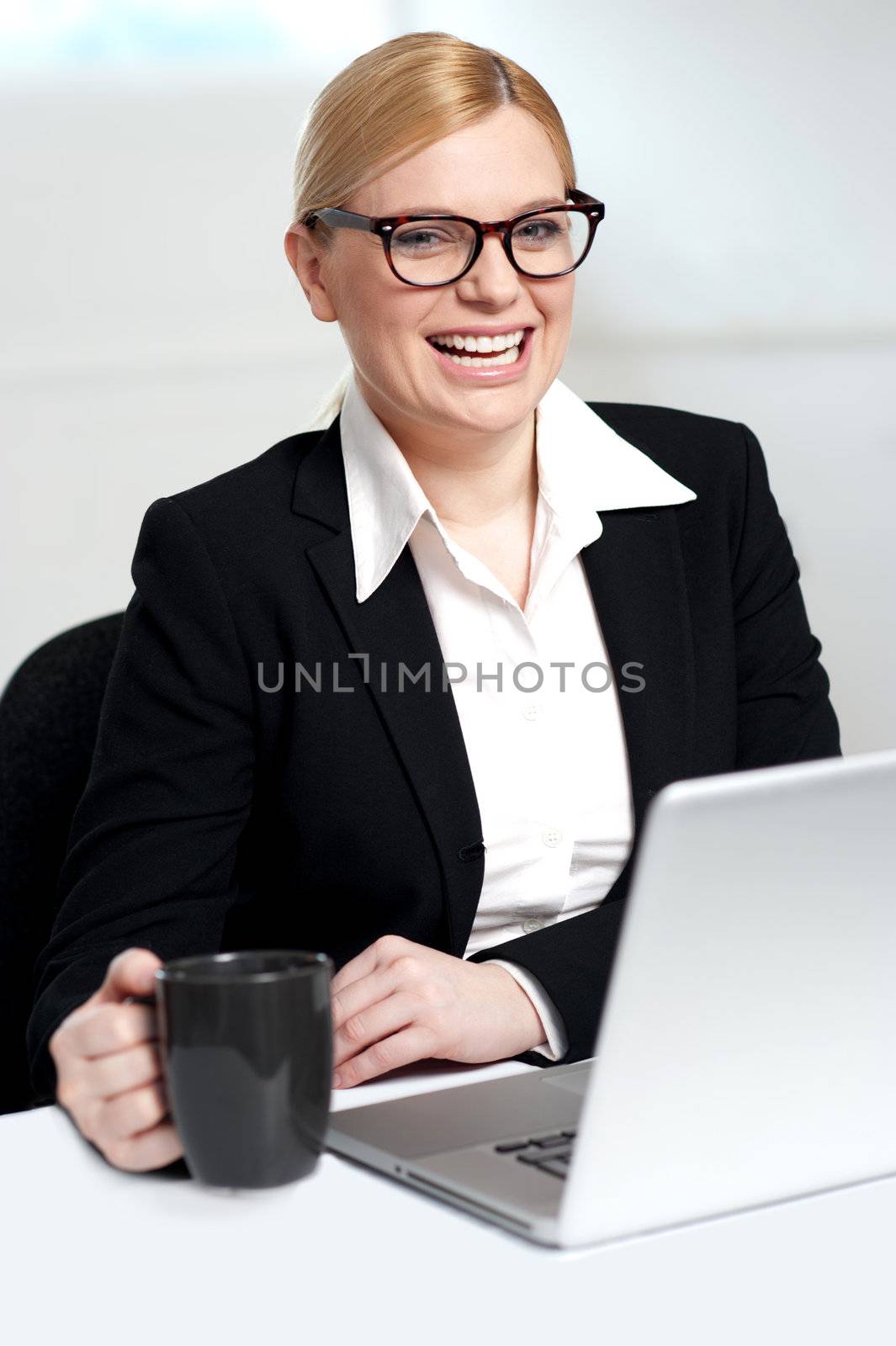 Attractive female smiling with black coffee cup in hand. At work desk
