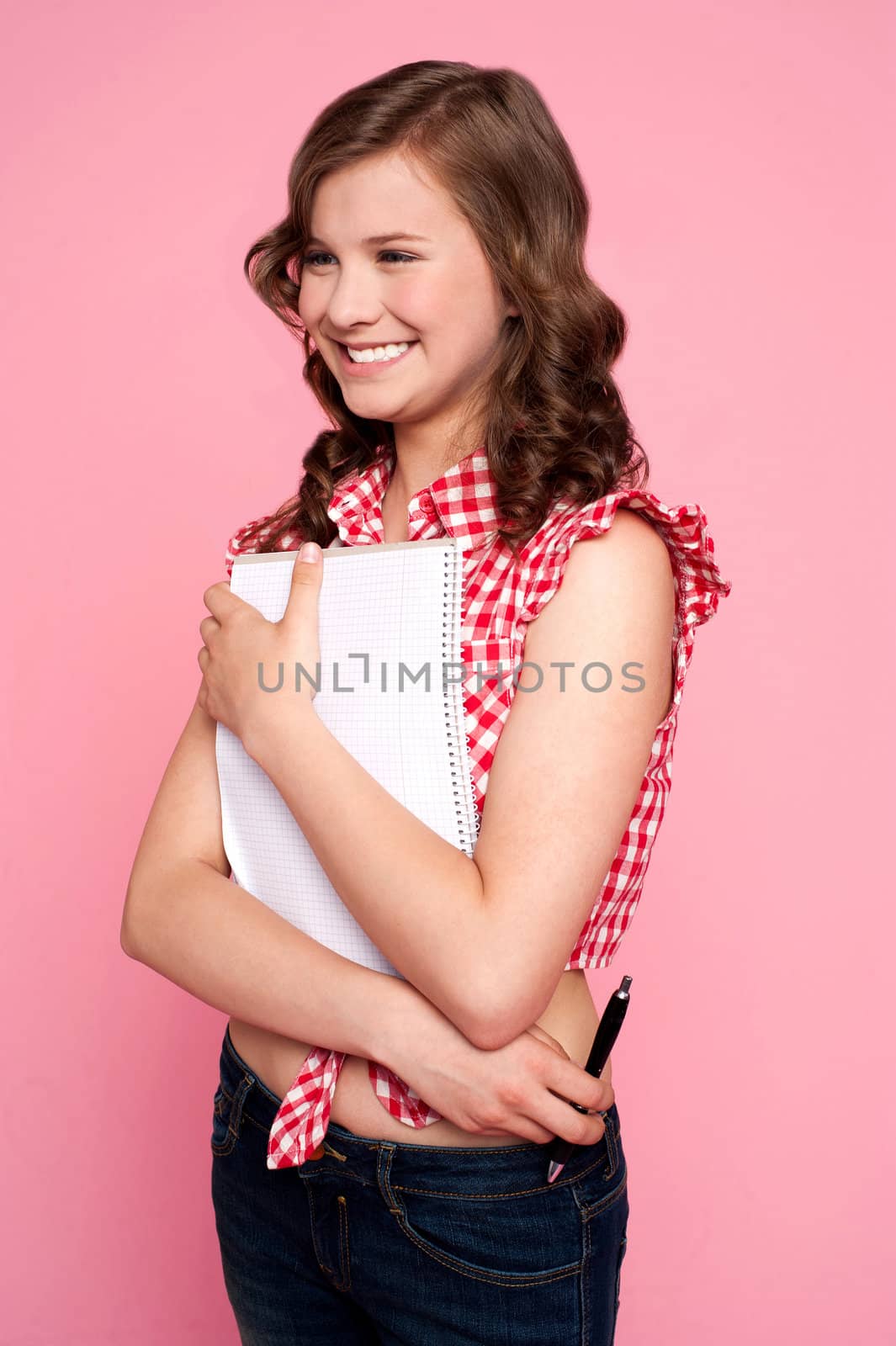 Trendy young girl posing with spiral notepad and looking away