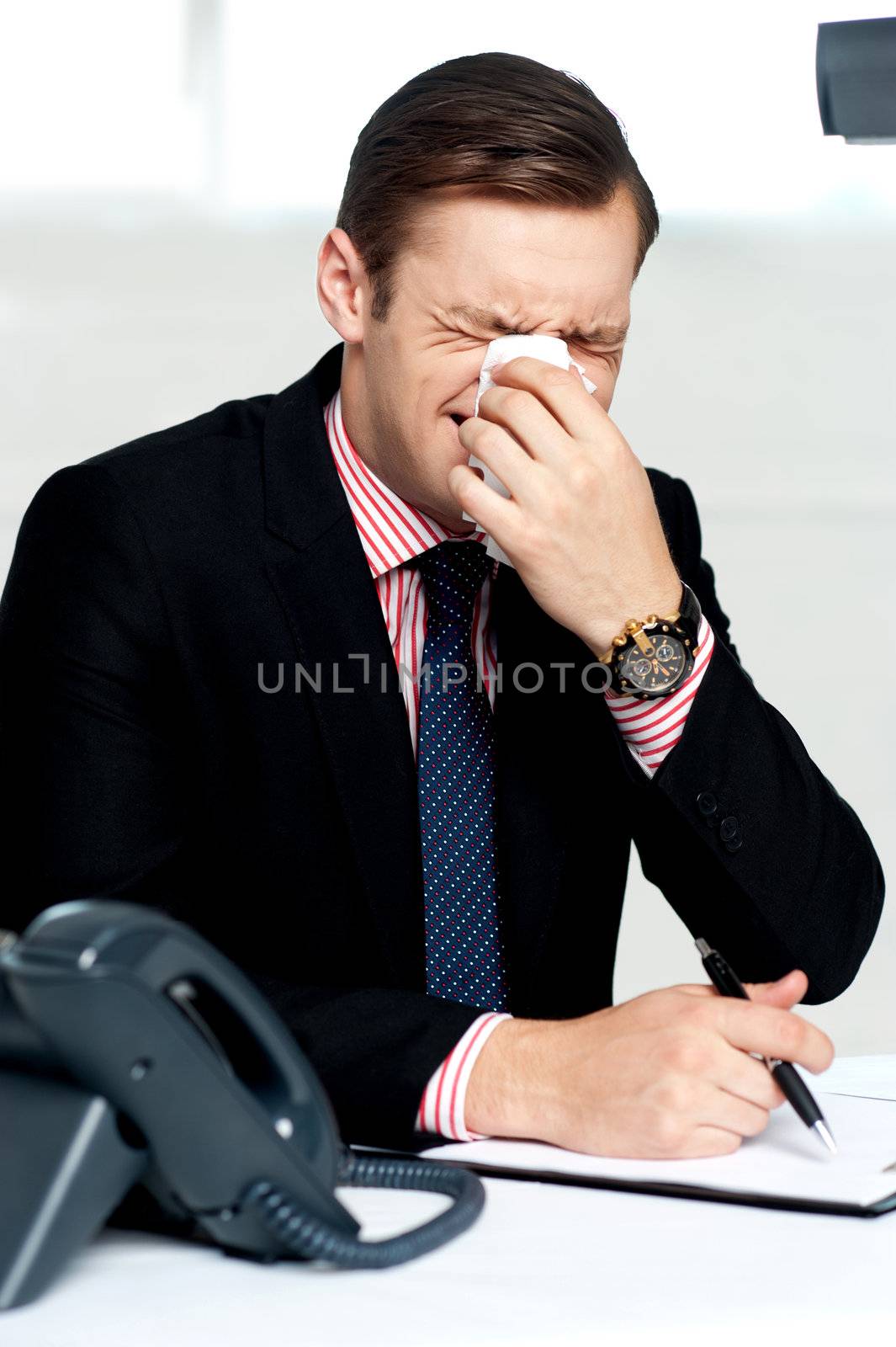 Young man having severe cold. Sneezing and cleaning nose with tissue paper