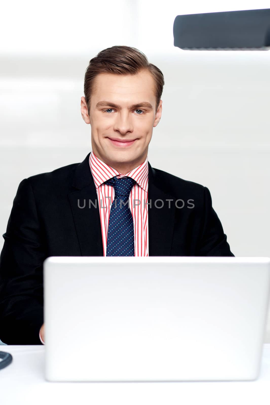 Attractive smiling man operating a laptop isolated against white background