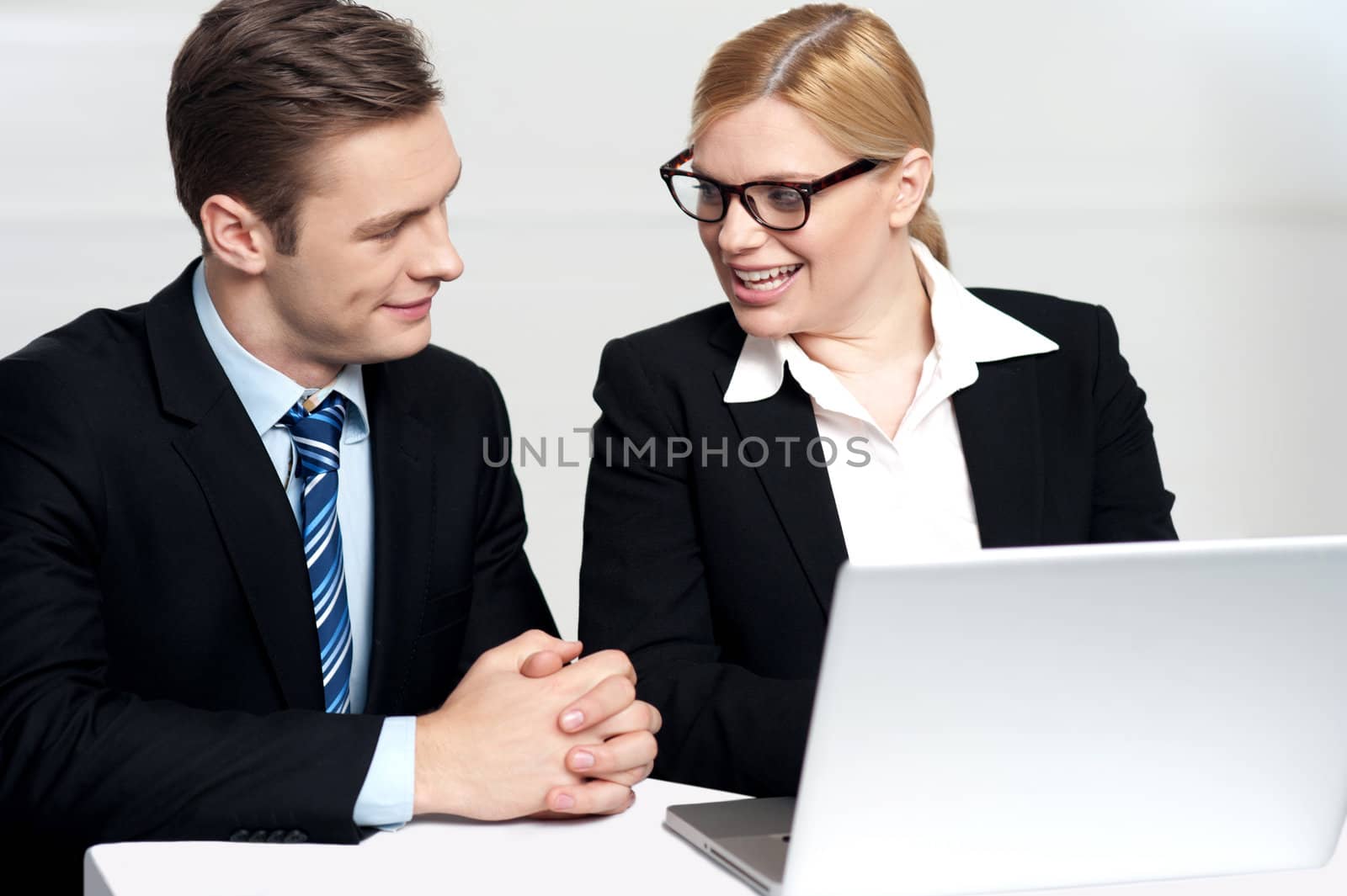 Businessman discussing deal with secretary sitting in front of laptop