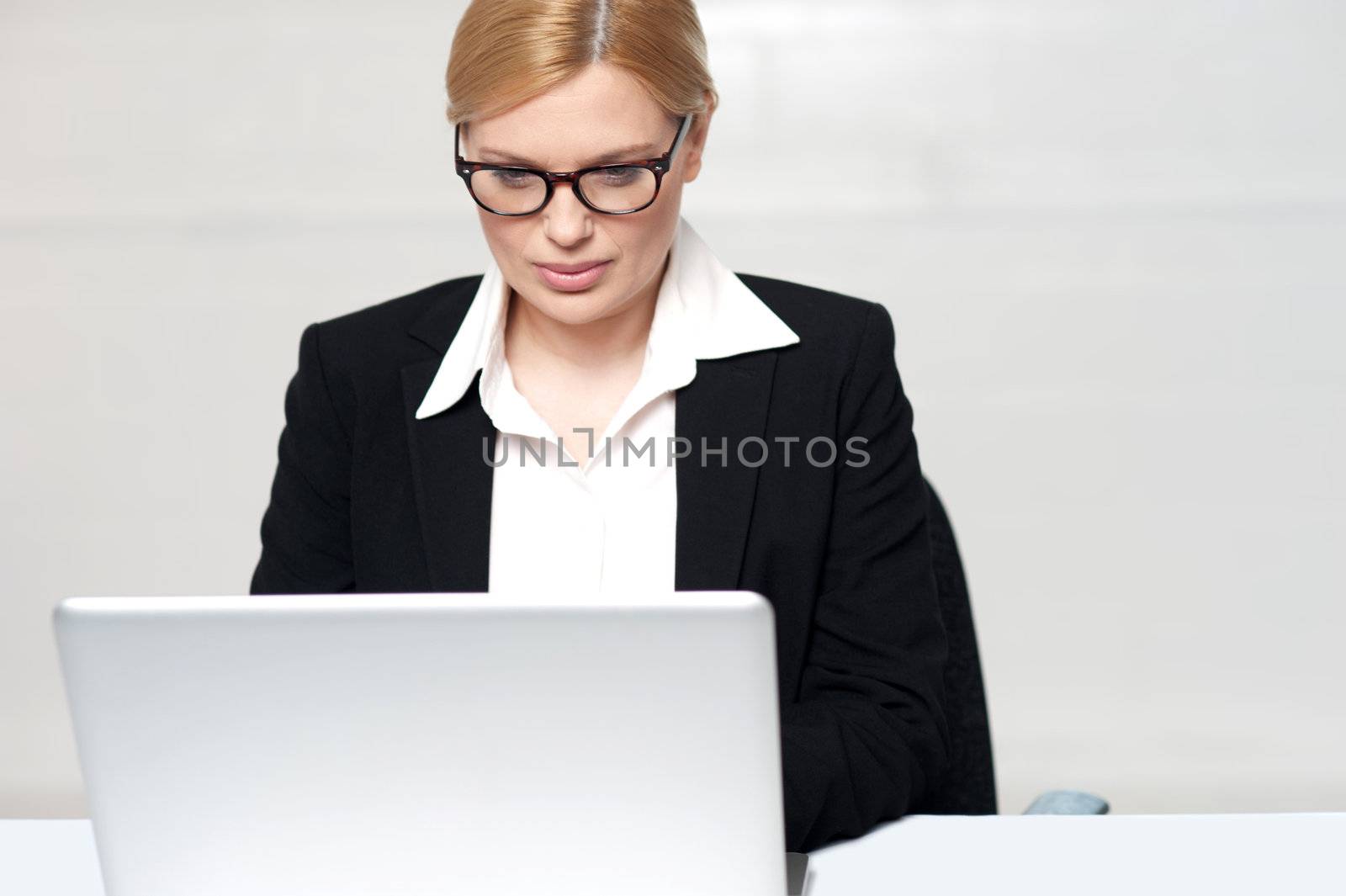 Corporate lady working on her laptop against gray background