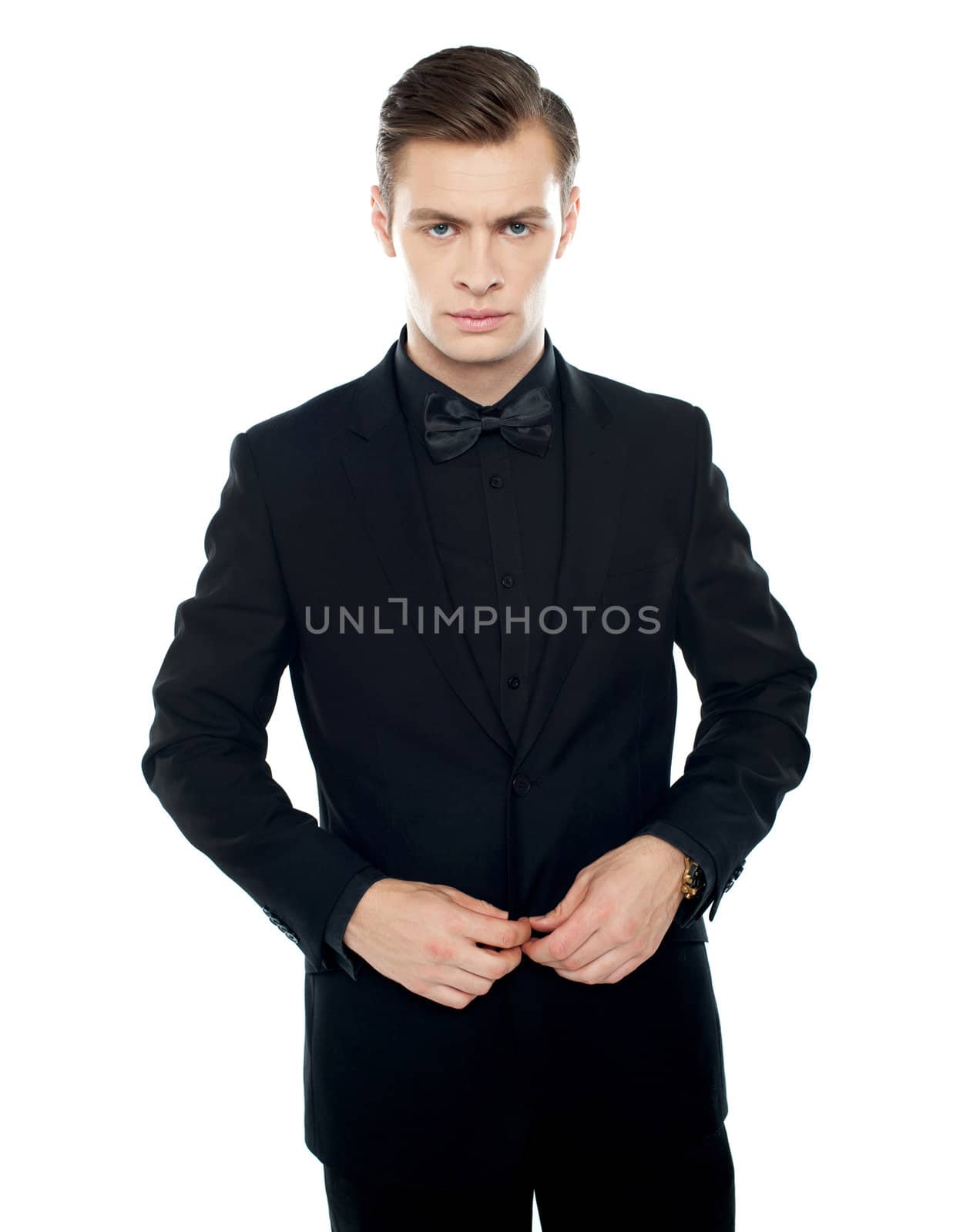 Serious young man tucking coat button isolated over white background