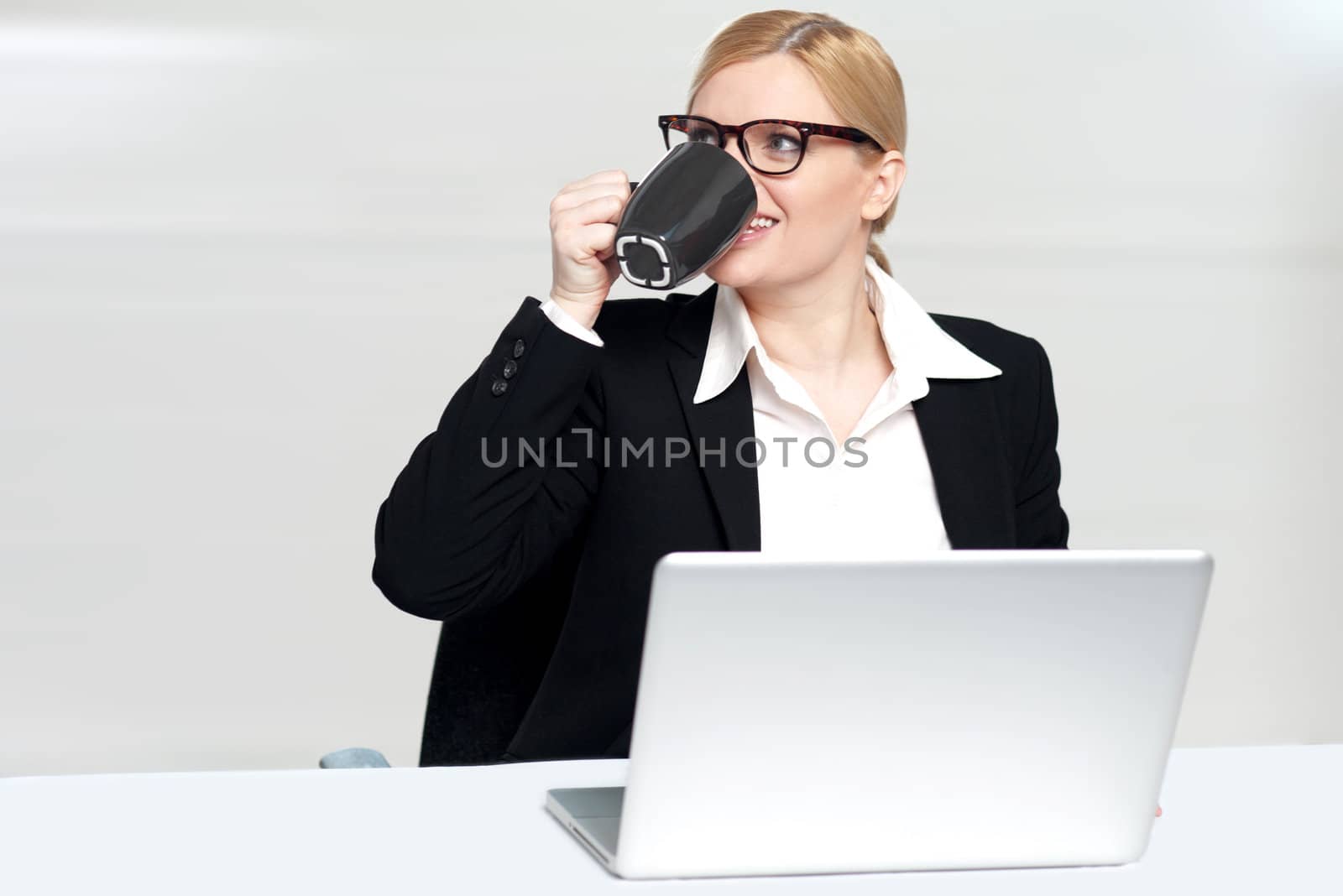 Businesswoman enjoying coffee at work desk. Indoor shot