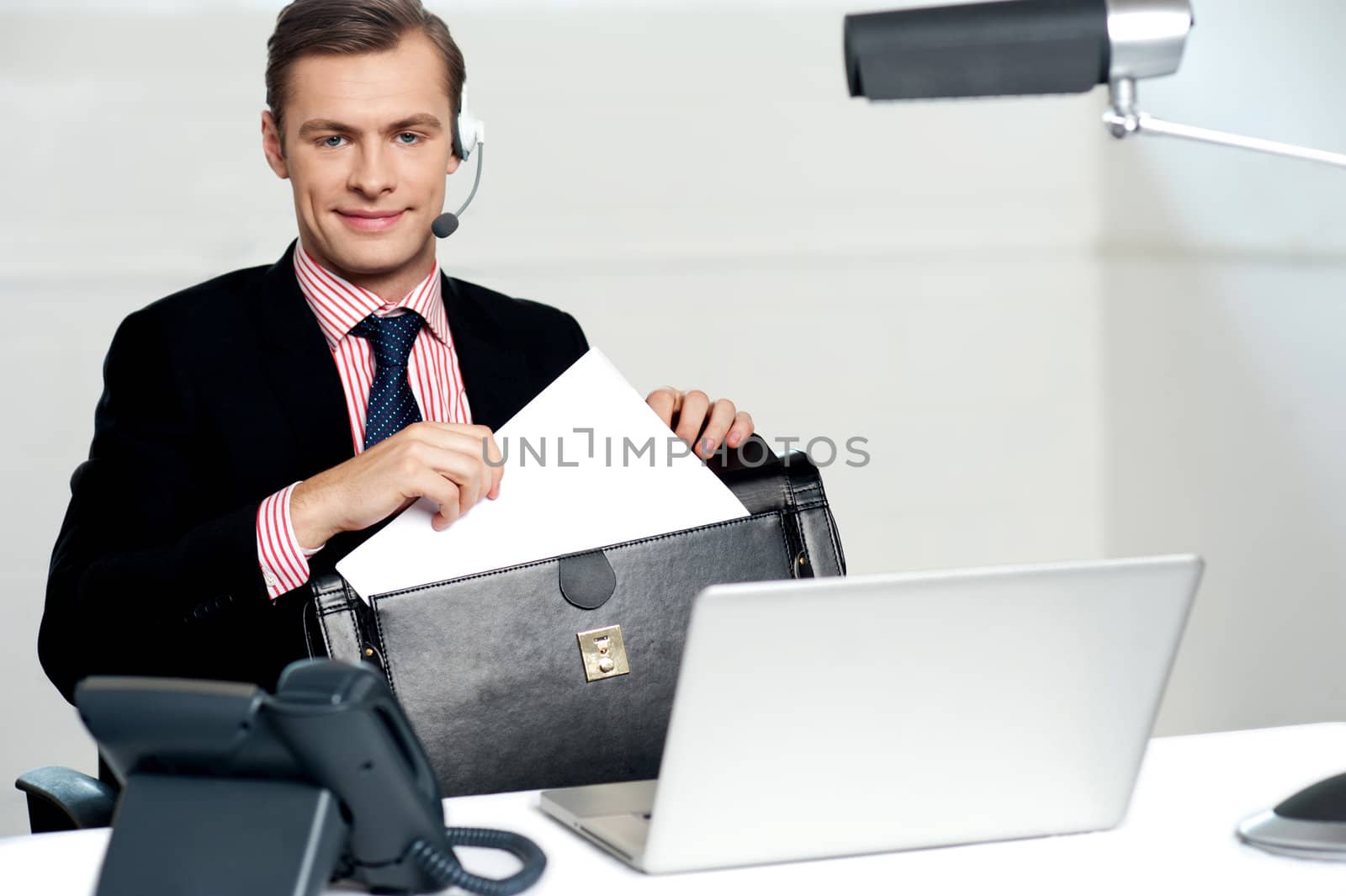 Male call centre executive arranging paper works and keeping them safely in bag