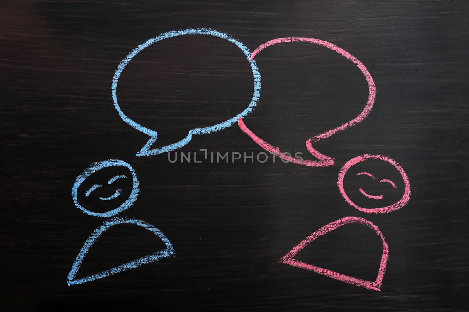 Chalk drawing of blank speech bubbles with human figures on a blackboard background