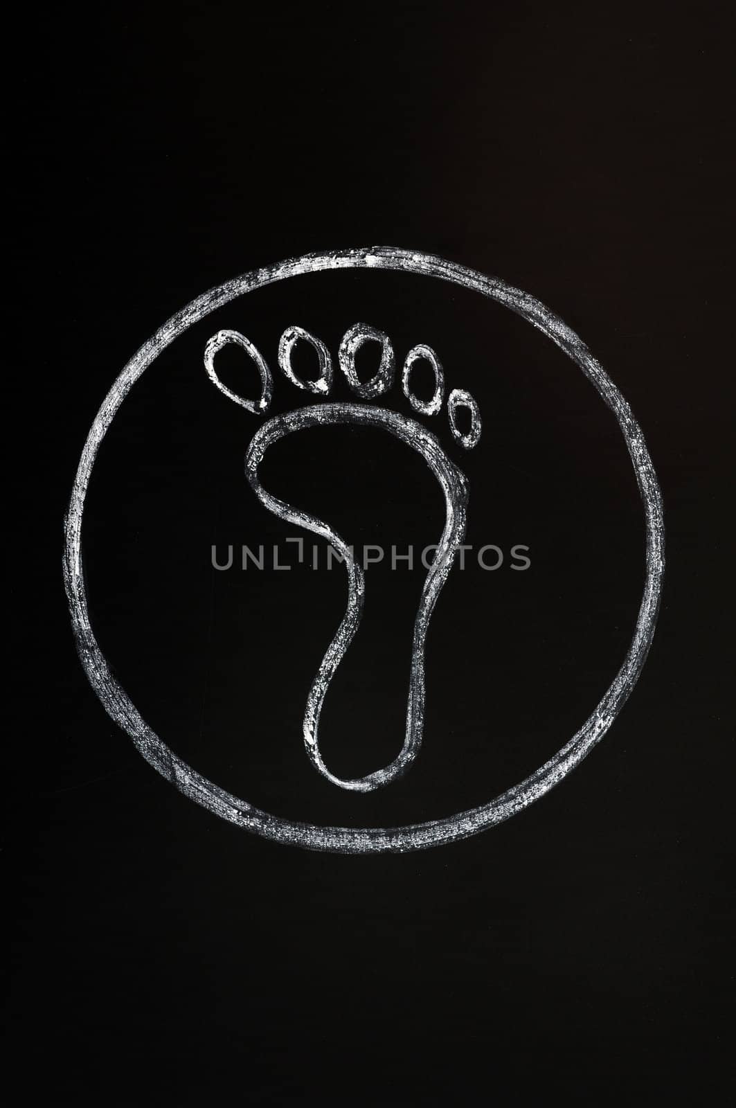 Chalk drawing of footprint symbol on a blackboard background with a circle