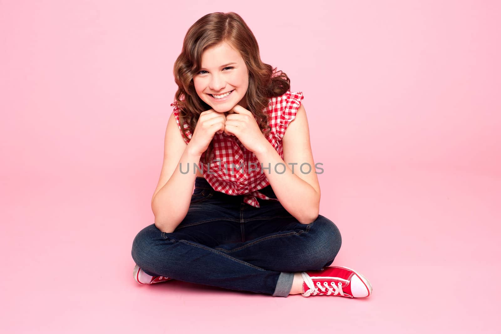 Caucasian girl sitting with hands on chin against pink background