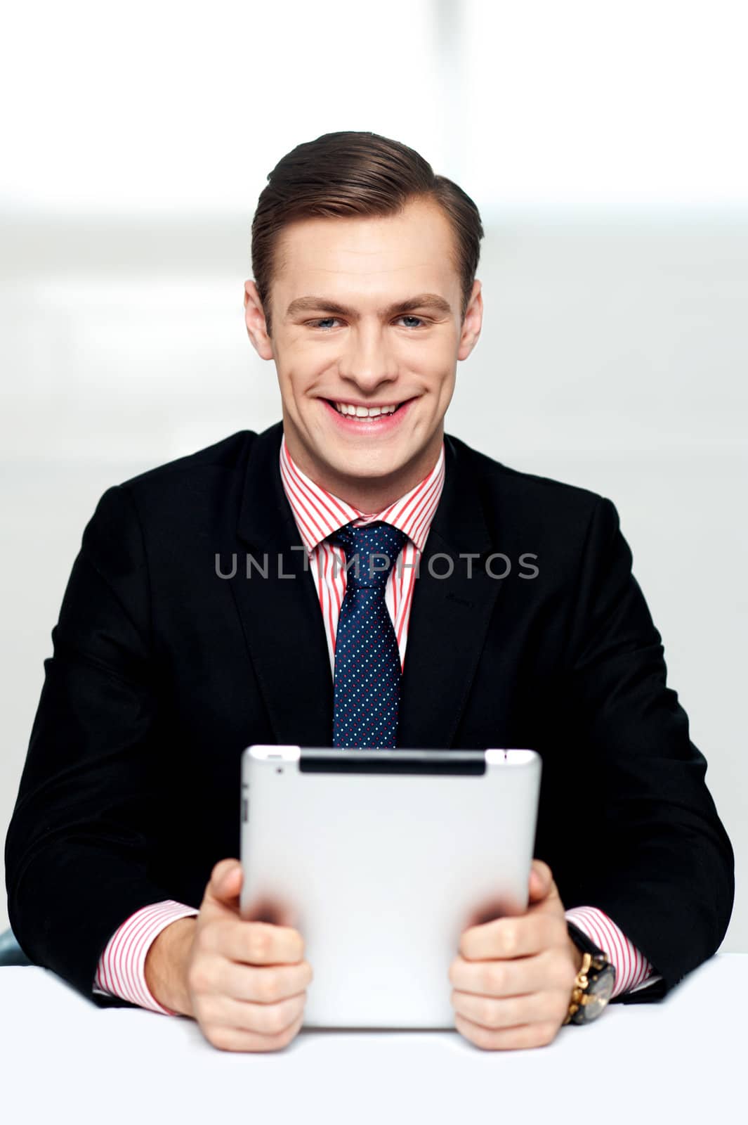Cheerful male executive holding touch screen enabled digital device