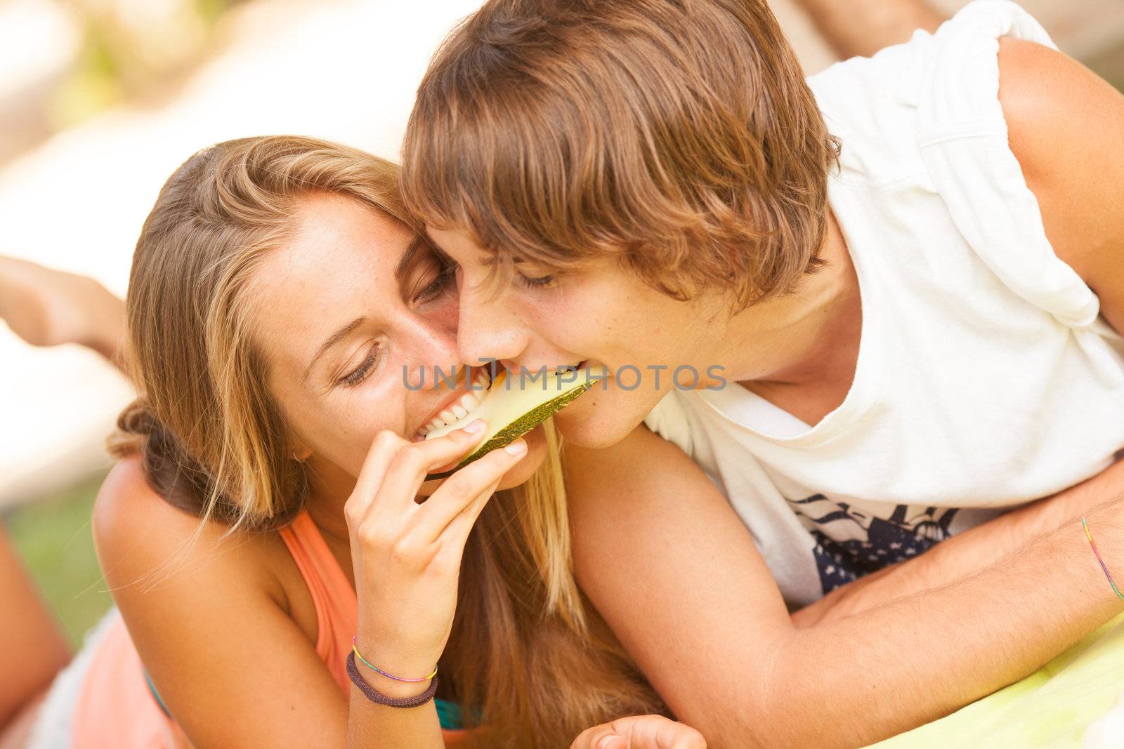 Portrait of a young beautiful couple eating melon by Lcrespi