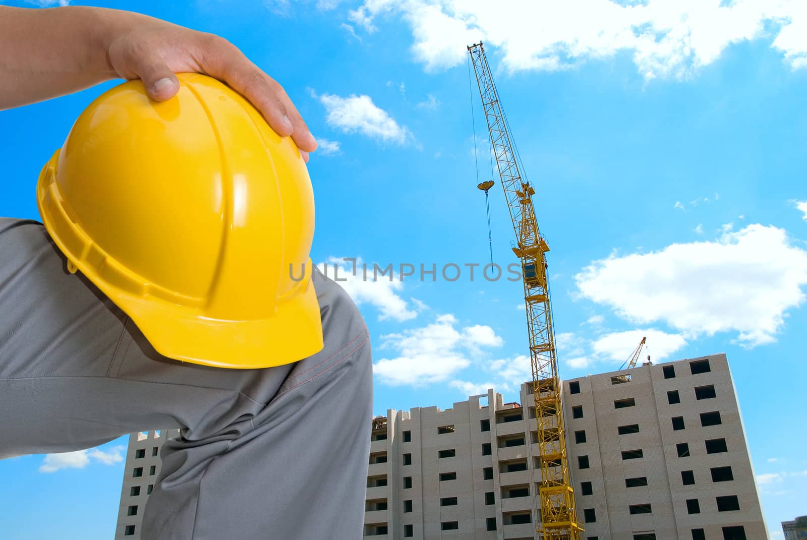 Building crane and builder under construction on blue cloudy sky