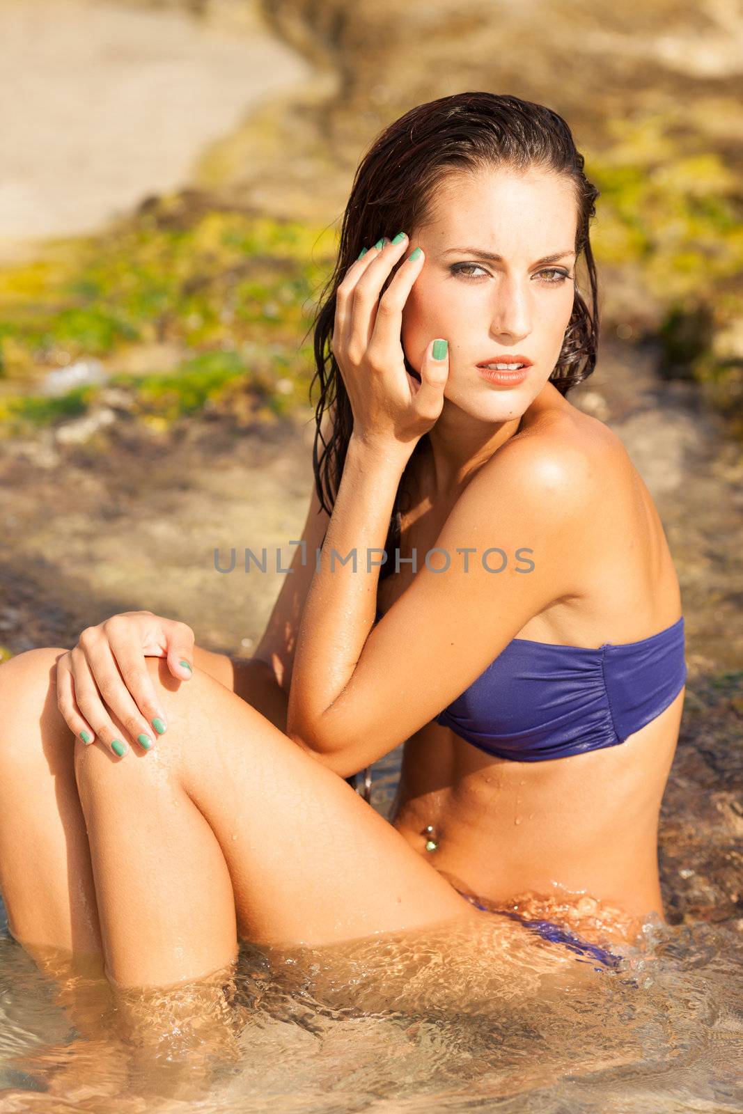 Portrait of sexy model enjoying a bath in the ocean with rocks
