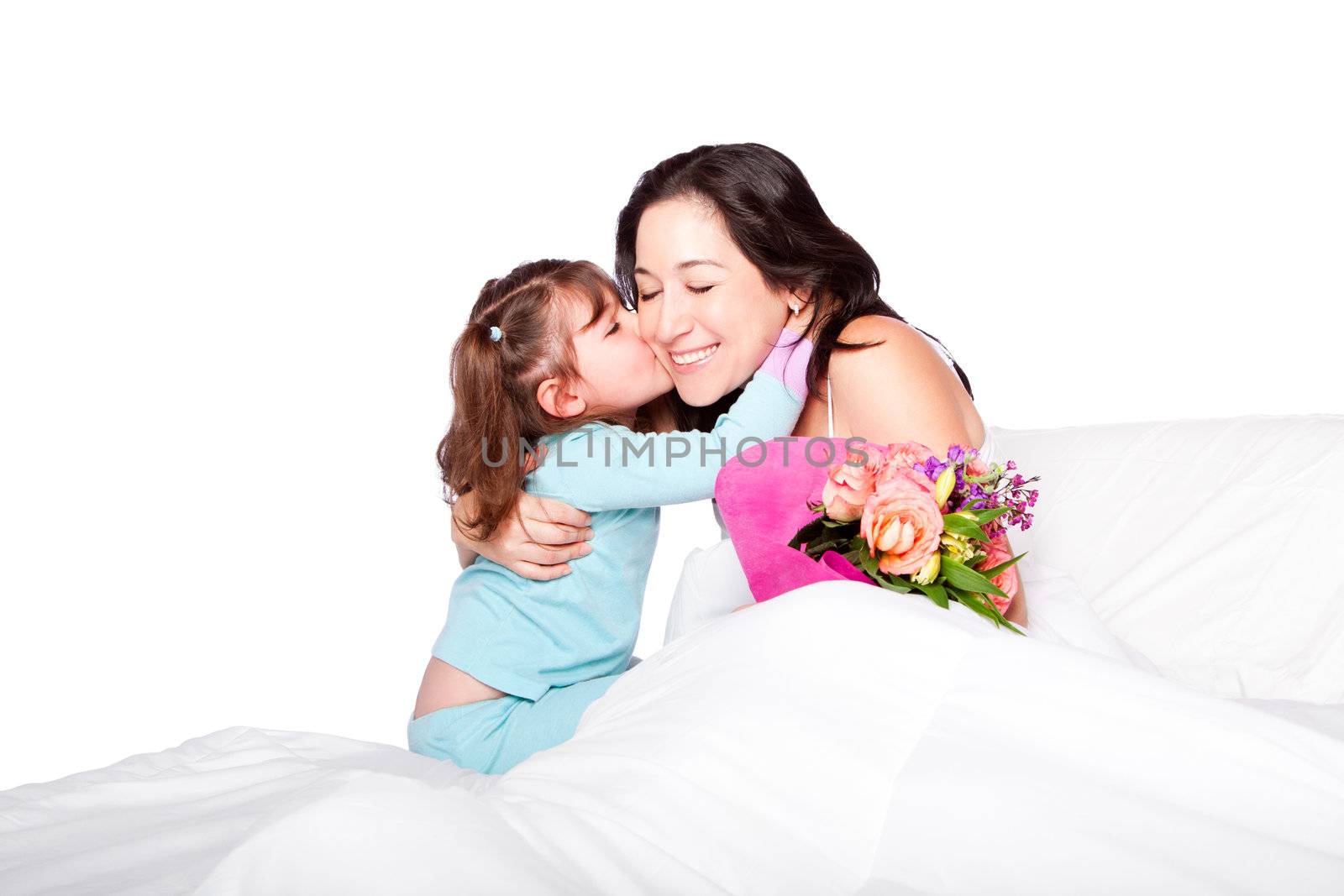 Cute child giving mother in bed a kiss on cheek and flowers, mother day or hospital concept, isolated.