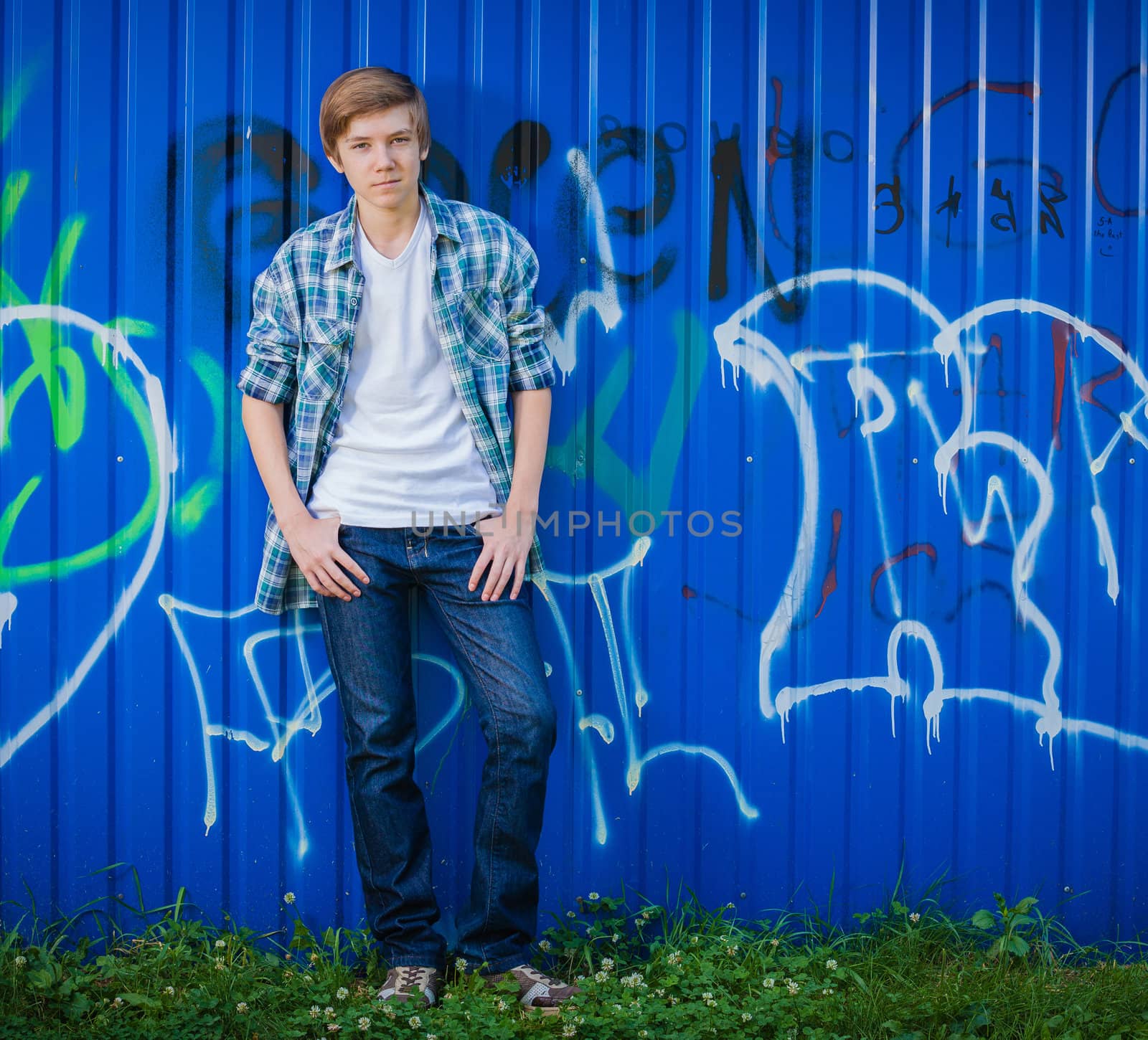 Young smile teenager in front of blue graffiti