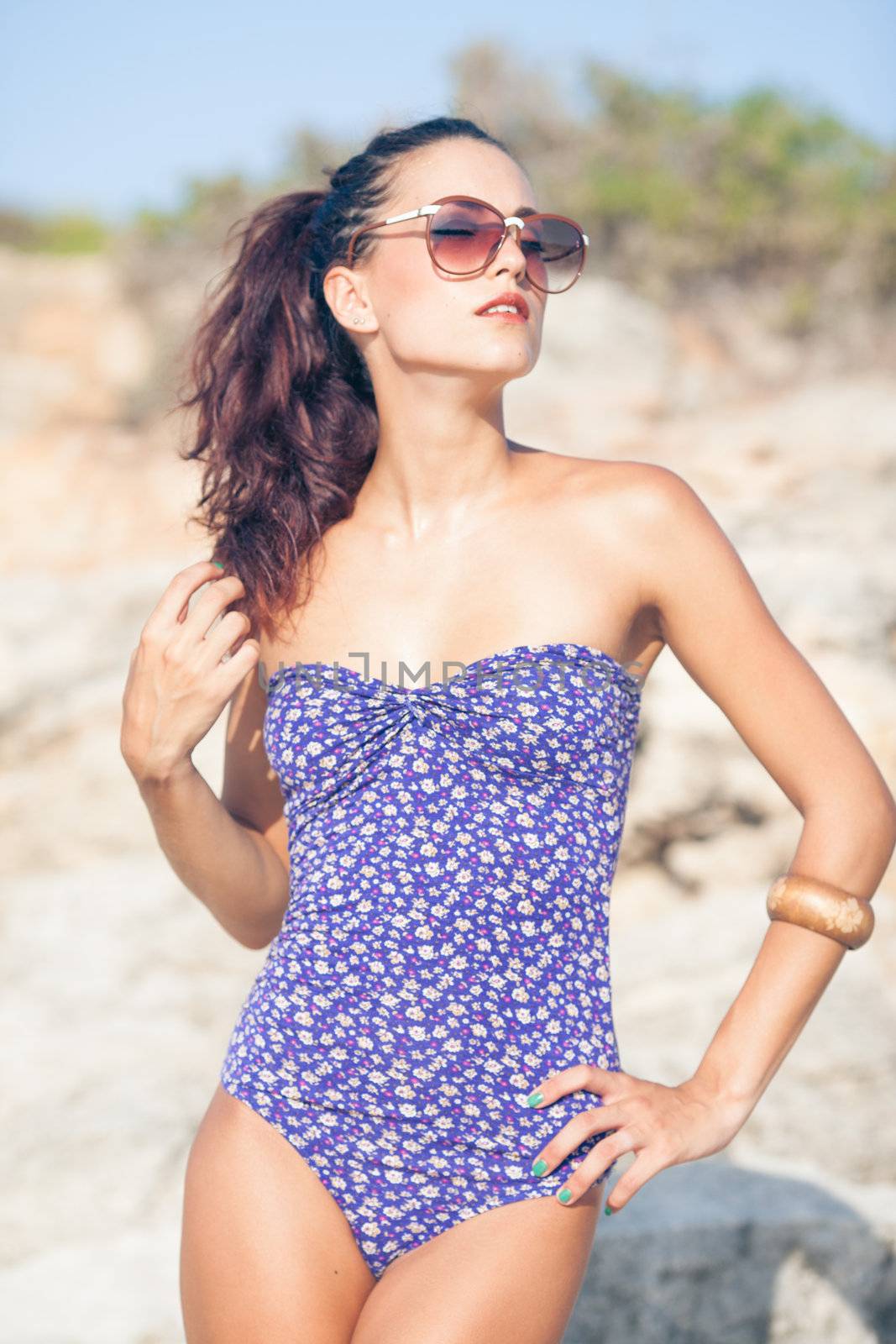 Sexy vintage model in swimsuit posing on the beach with glasses