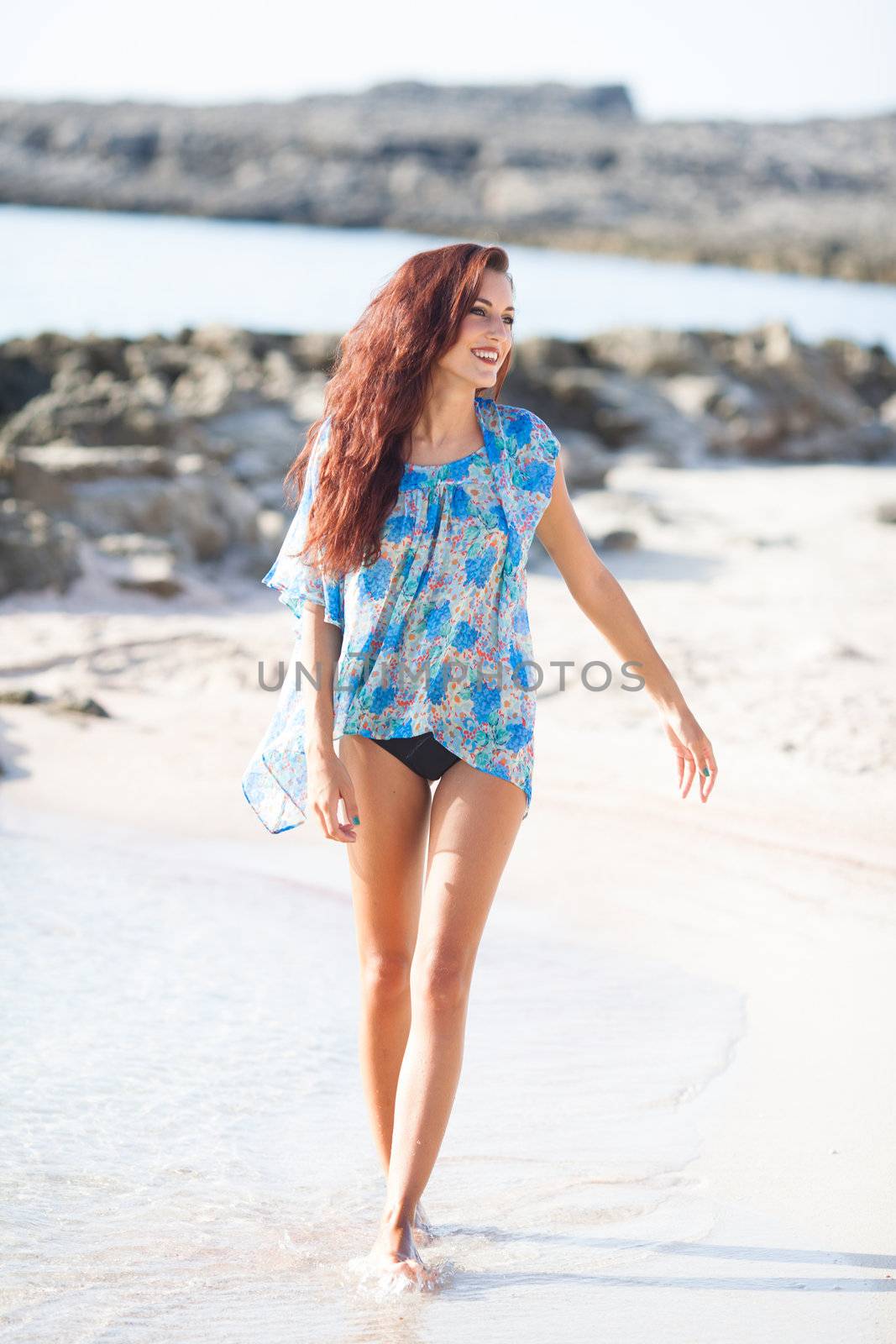 Young beautiful woman having fun on the beach waring blue shirt