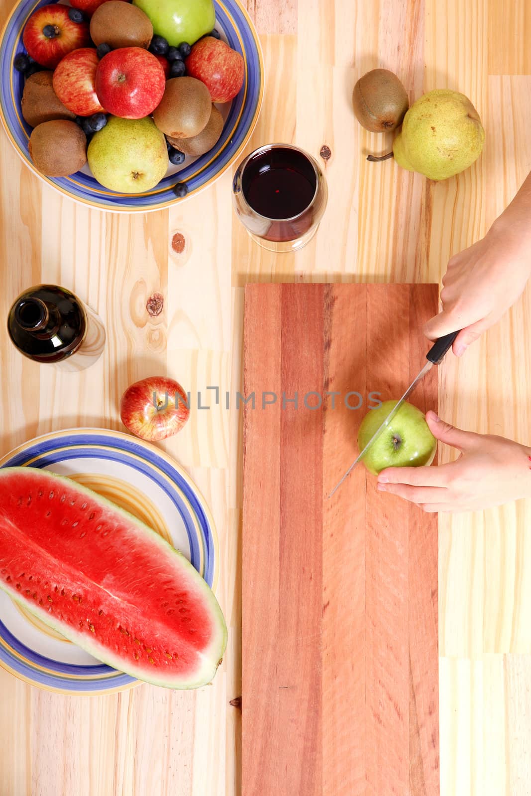 A young adult woman cutting fruits in the kitchen.