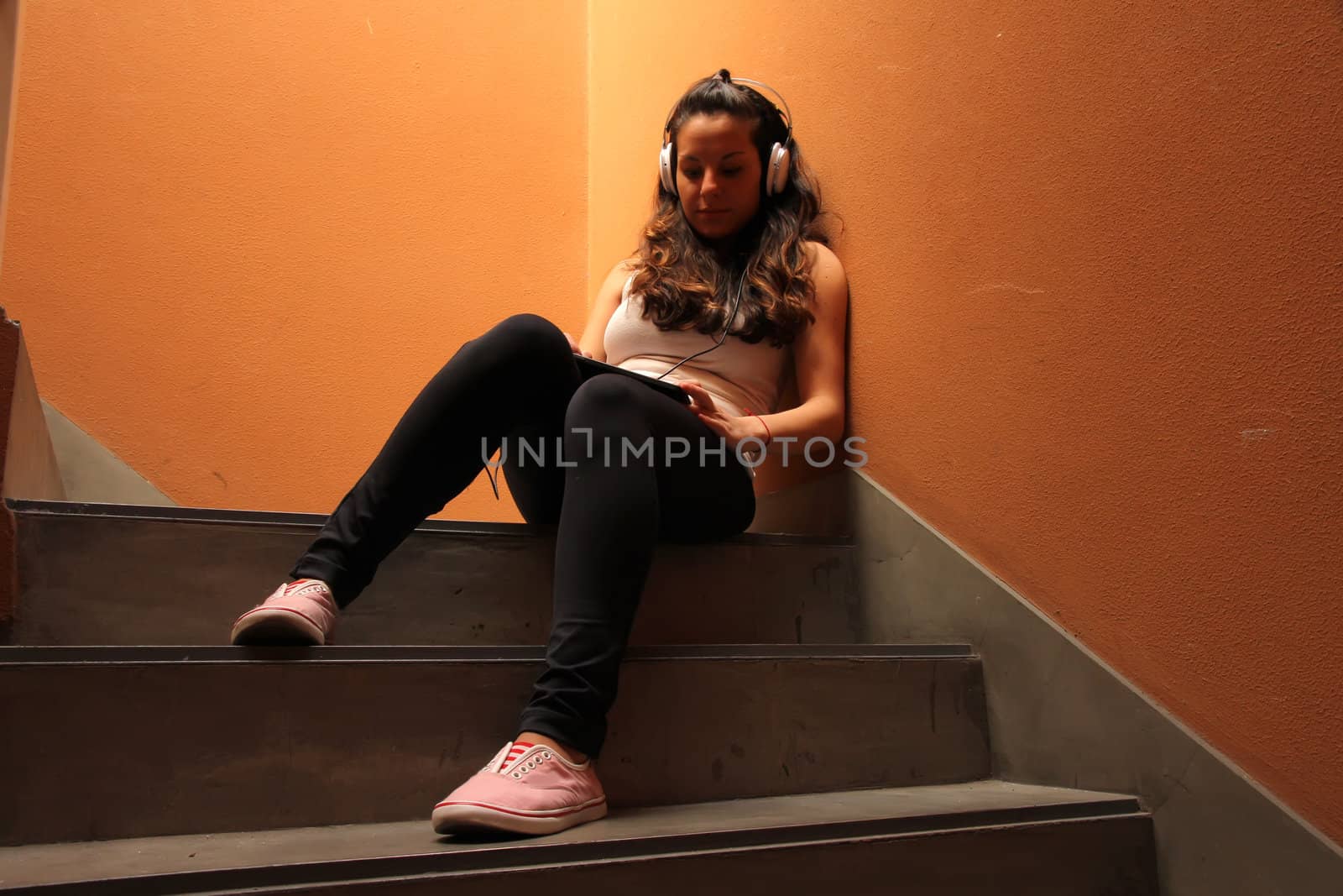 A young woman listening to melancholic Music sitting in the stairway.