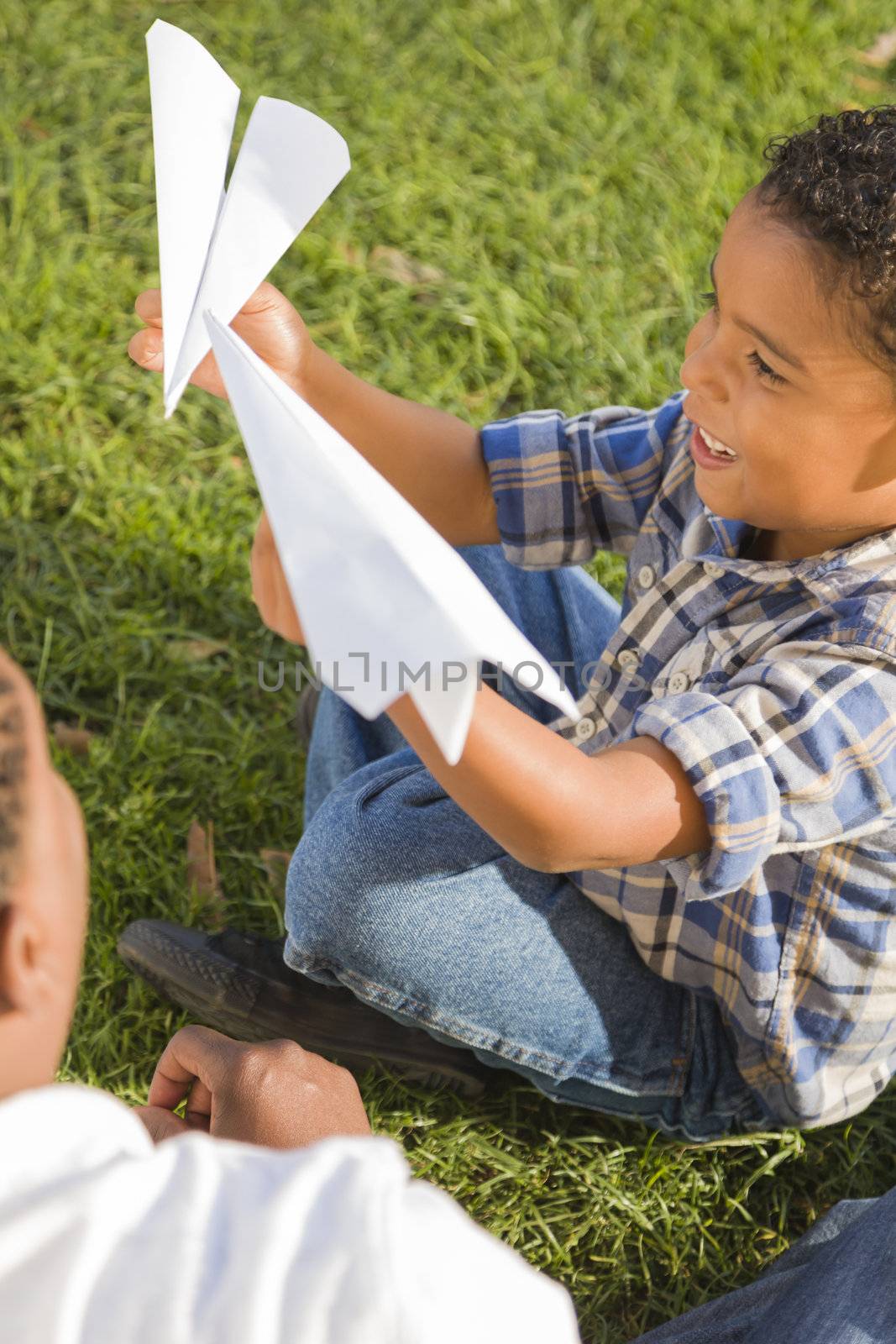 Mixed Race Father and Son Playing with Paper Airplanes by Feverpitched