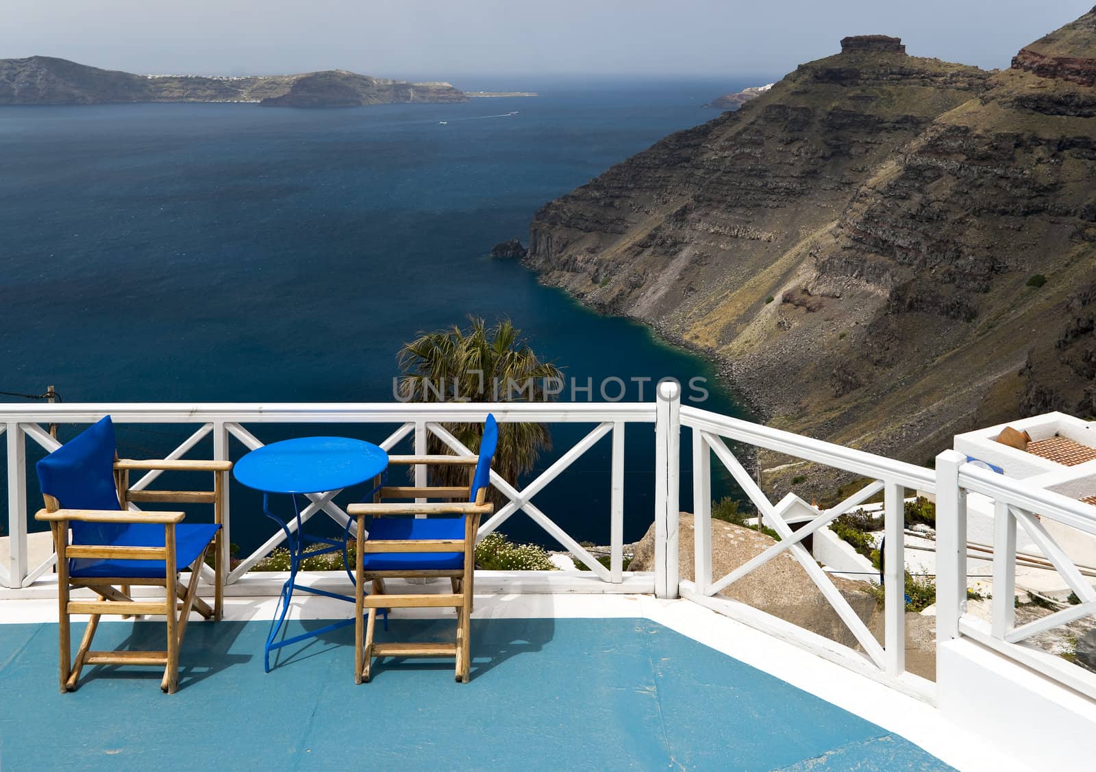 Caldera view in Santorini island with blue chairs and the table 