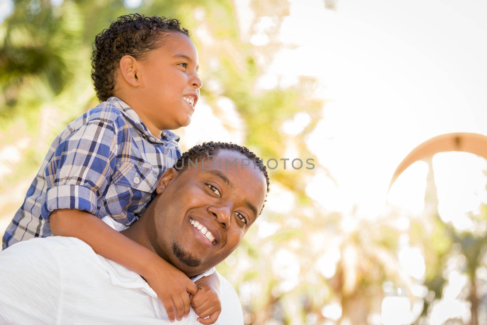 Happy Mixed Race Father and Son Playing Piggyback in the Park.