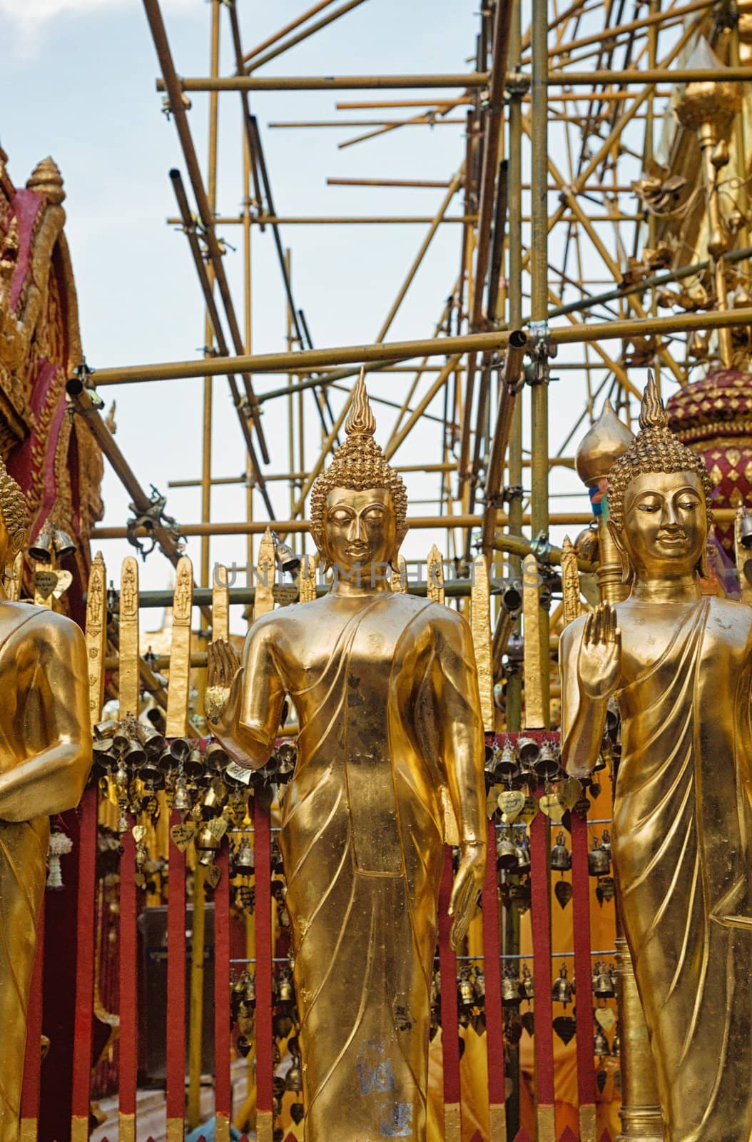 gold buddha images in front of golden temple being reconstructed