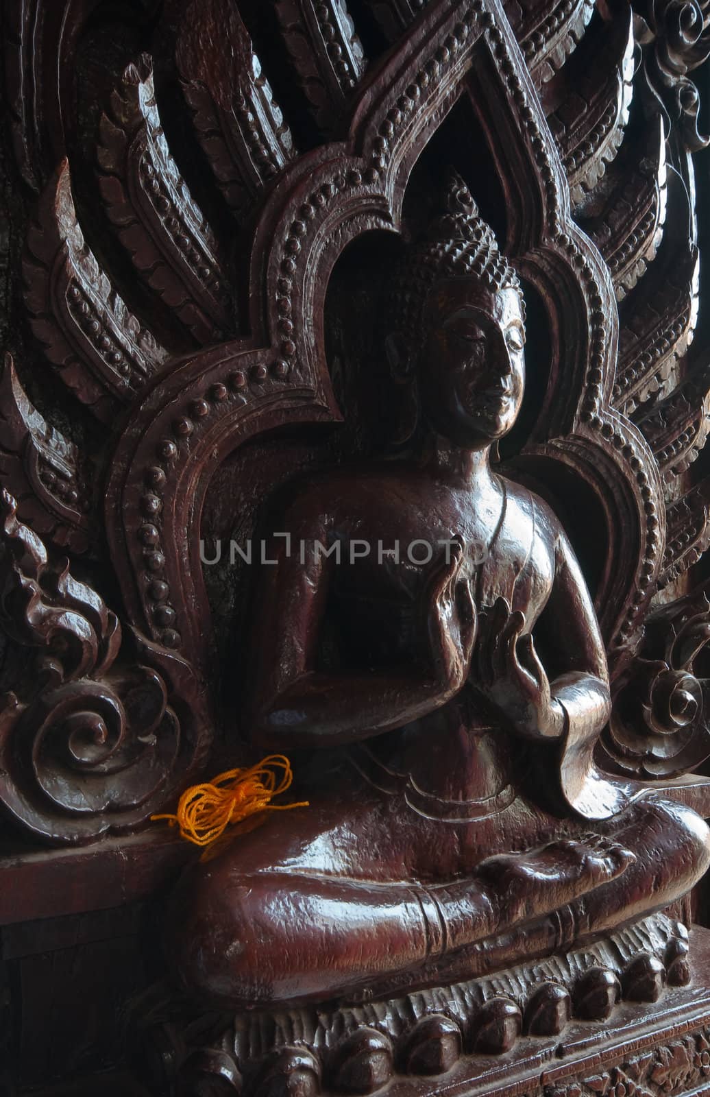 yellow string on a black Buddha figure on the wooden temple door in a Thai temple