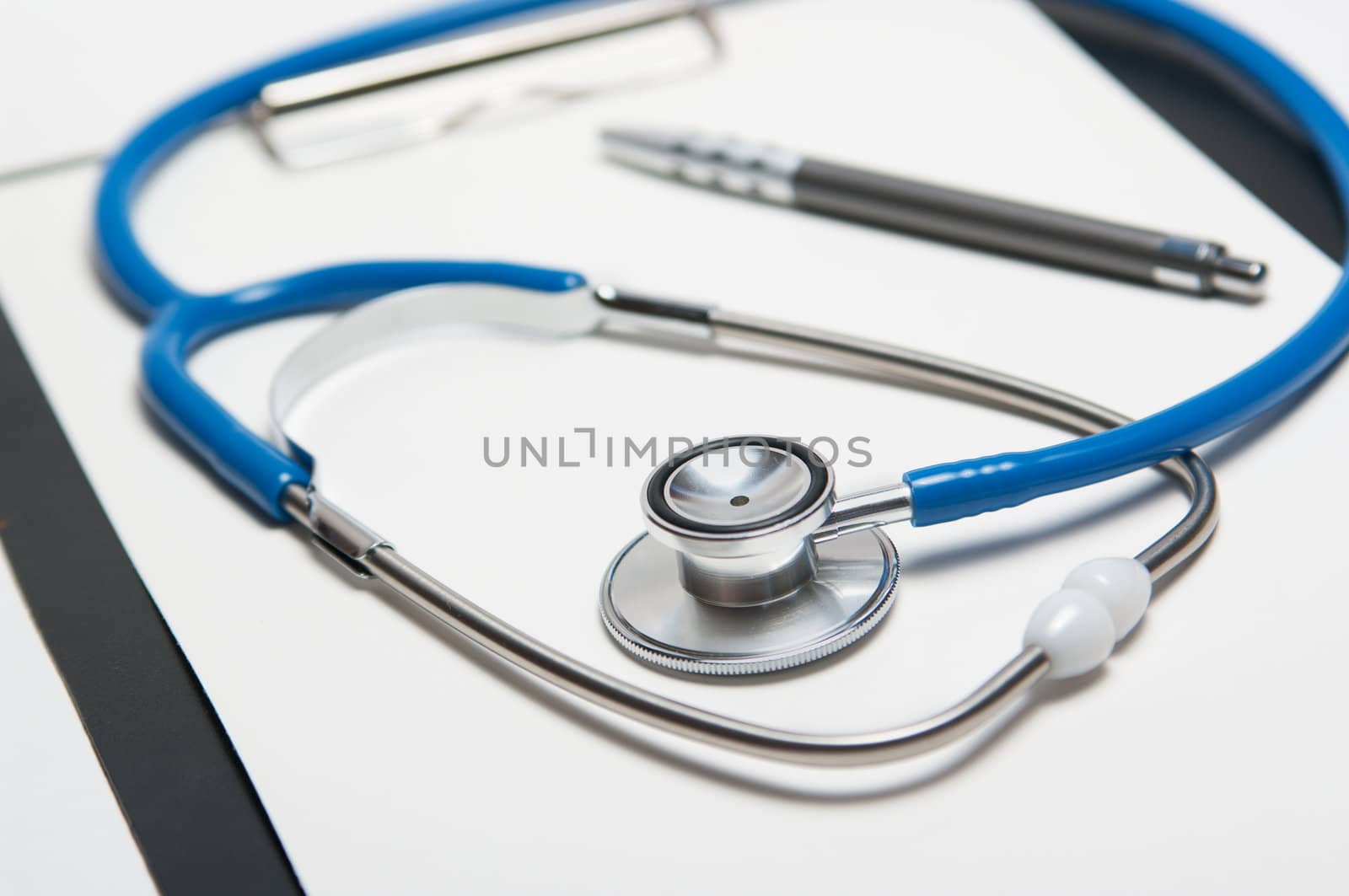 Stethoscope and pen on empty paper sheet