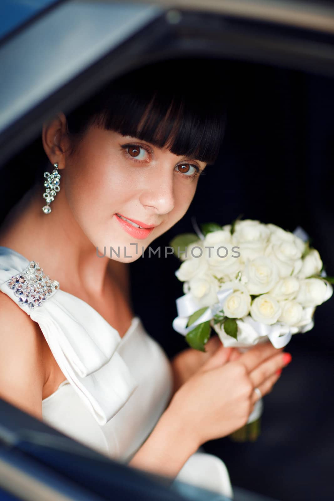 happy bride with flower bouquet siting in the car