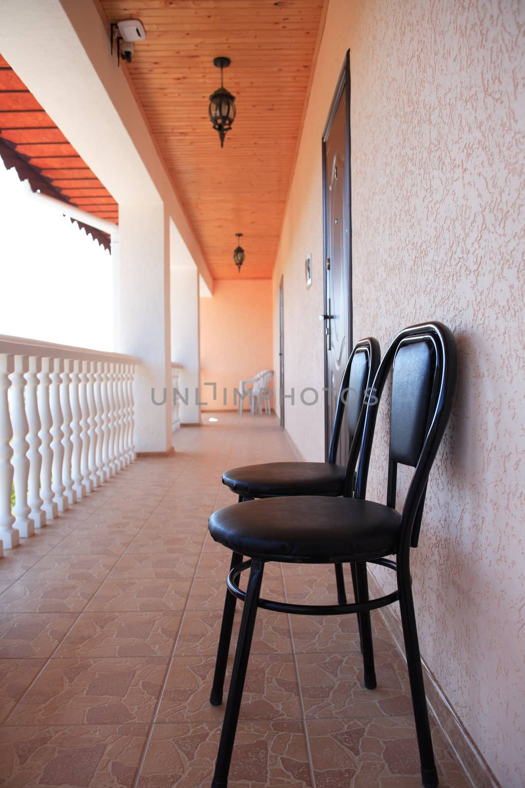 Pair of chairs standing on long terrace with white railing