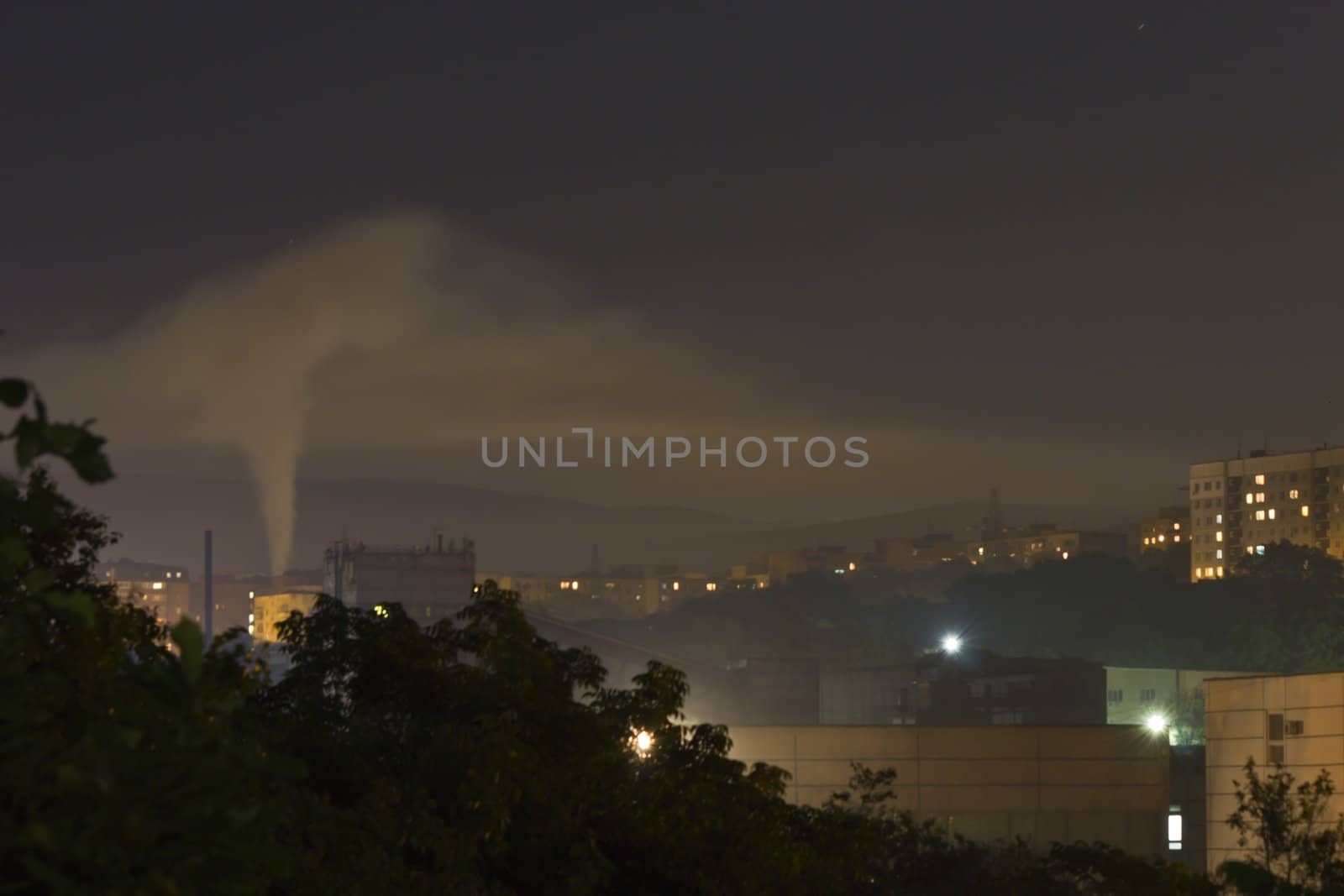 Smoke from a pipe in the city at night