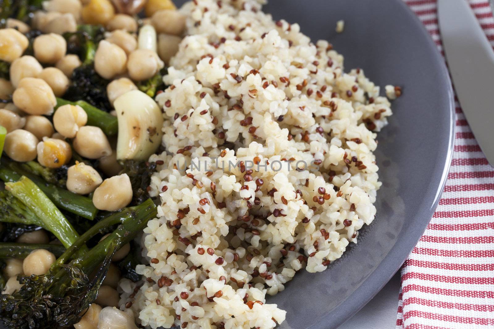 Steaming plate of broccoli and chickpeas served with bulgar and quinoa mix.