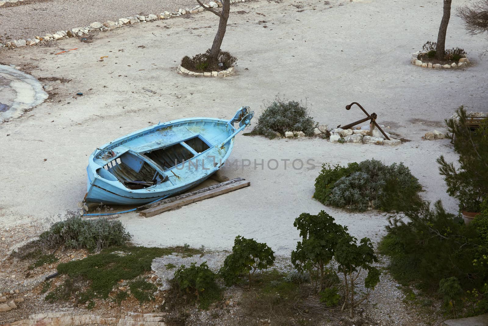 Old blue wooden boat marooned on beach.