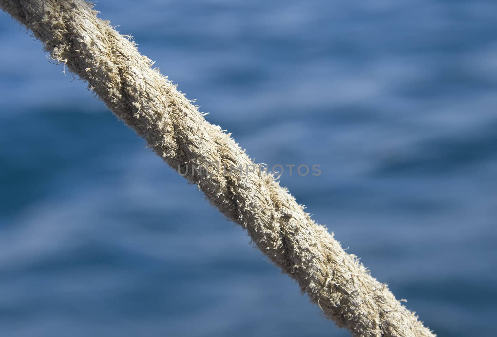 Stretched tight thick rope against blue sea water