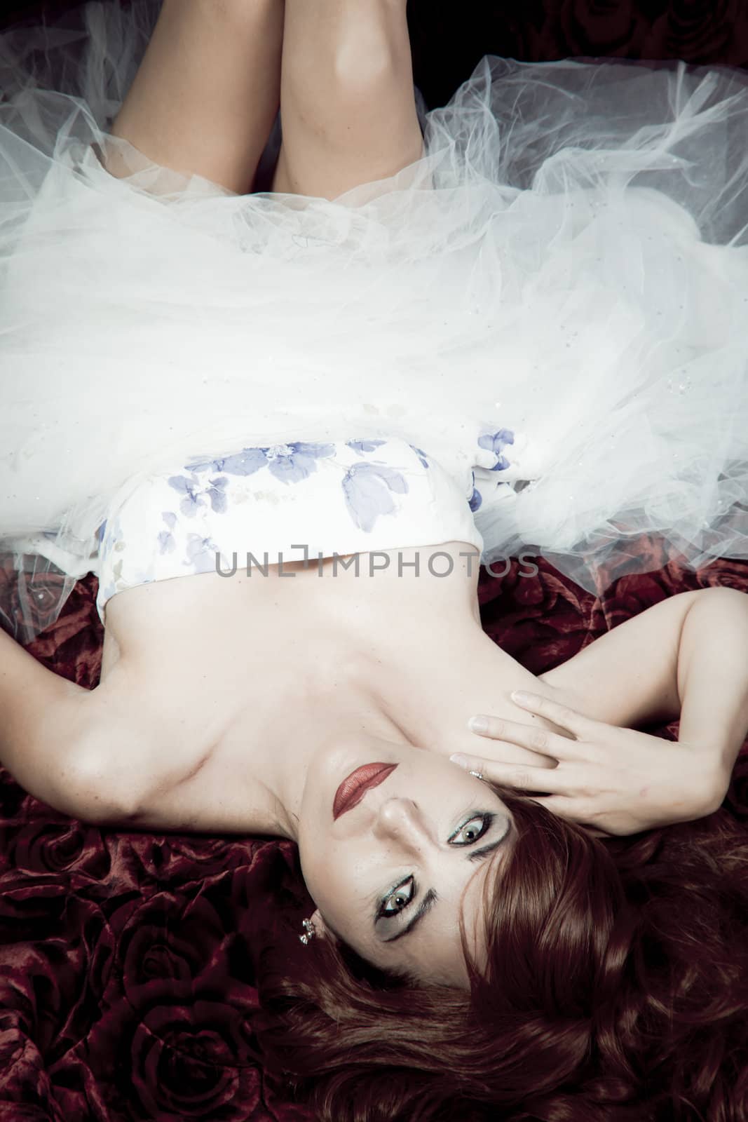 Beautiful redheaded woman lying on a bed of roses in black and white