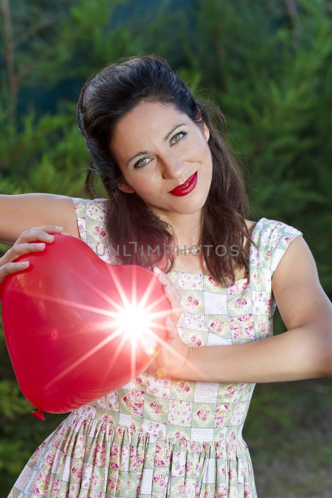 Attractive happy smiling brunette woman holding one red valentine heart, woman on park, concept of valentine's day