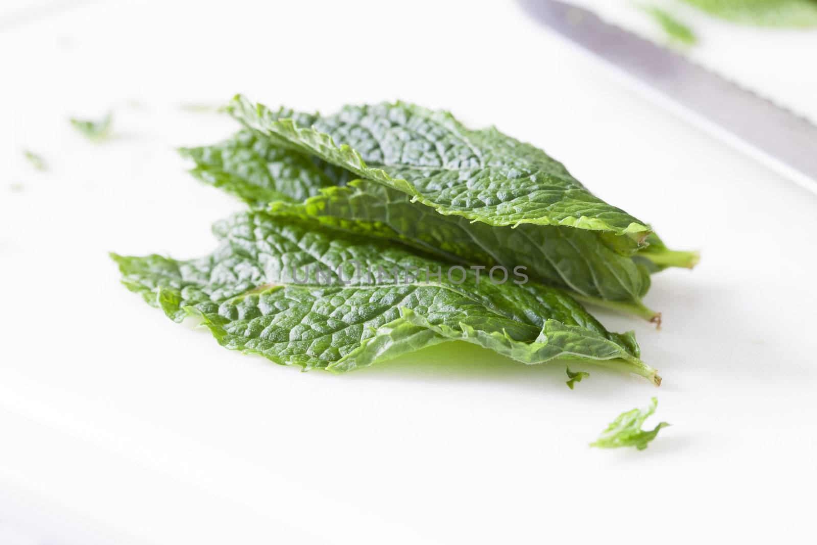 Mint leaves on cutting board with knife out of focus in the background