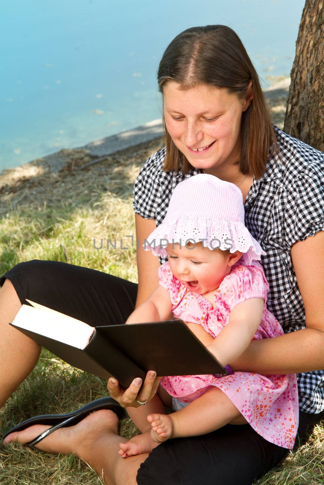 beautiful little girl reading book with her mother