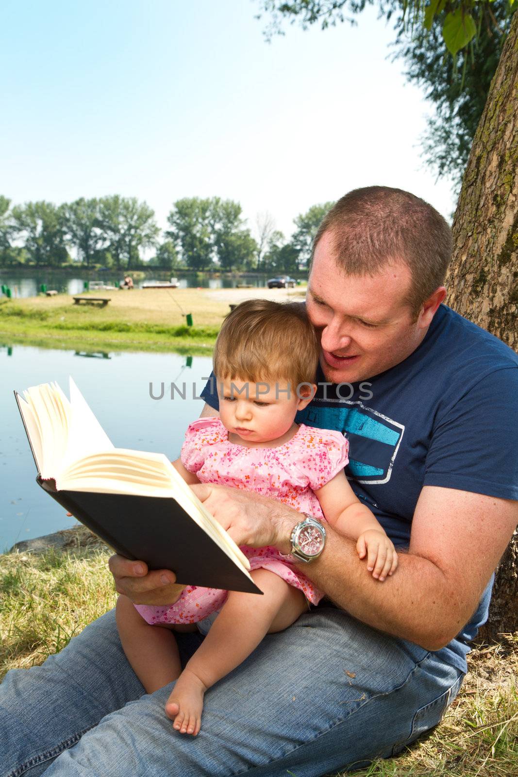 Father and little girl reading book together 