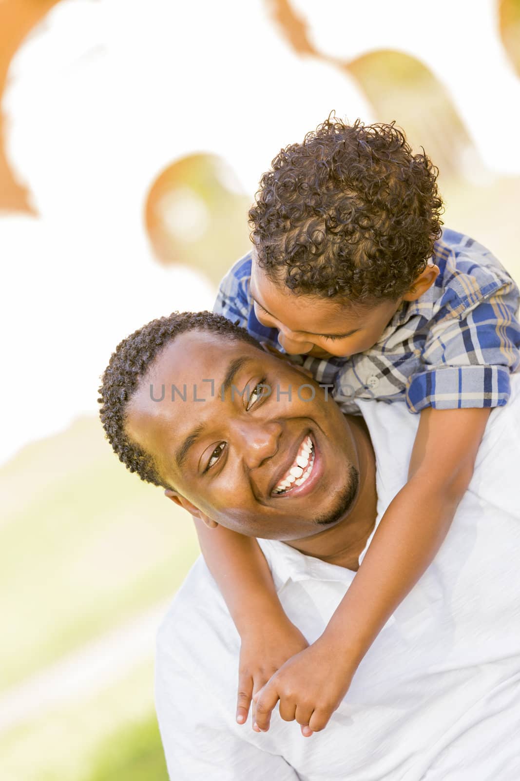 Happy African American Father and Mixed Race Son Playing Piggyback in the Park.