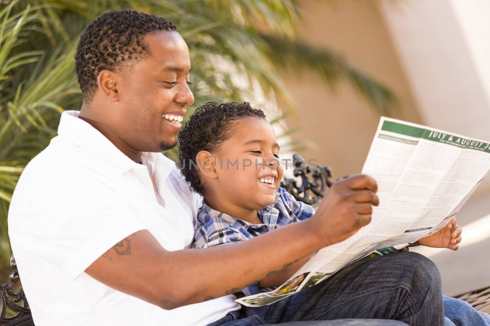 Mixed Race Father and Son Reading Park Brochure Outside by Feverpitched