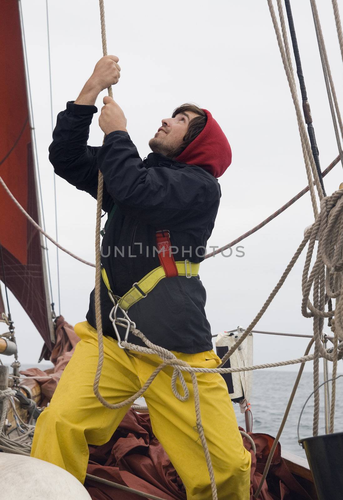 Young sailor on a ship's deck hoisting a sail