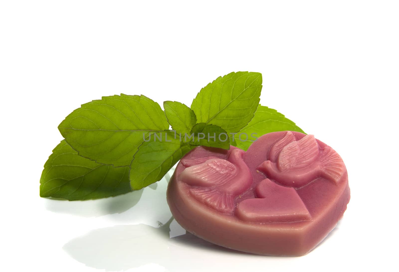 pink piece of soap in heart shape with green mint isolated on white